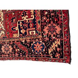 Persian Heriz red ground carpet, large central eight point medallion with projecting palmettes surrounded by small geometric motifs, decorated profusely with hooks, rosettes and animals, the busy border decorated with stylised foliate motifs within guard stripes 