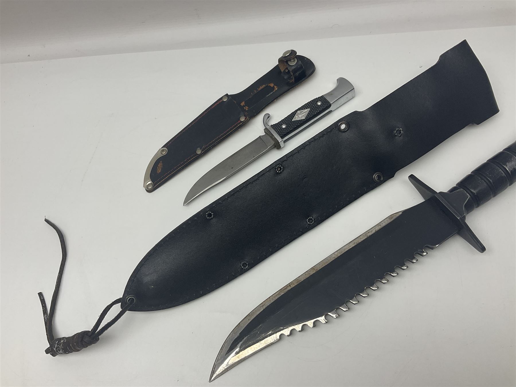 Post WWII scout knife, based on a Hitler Youth knife, in embossed leather sheath with scout emblem to handle, together with a similar example, also with scout emblem to handle, marked Whitby made in Germany, and a hunting knife with serrated edge, largest L39cm