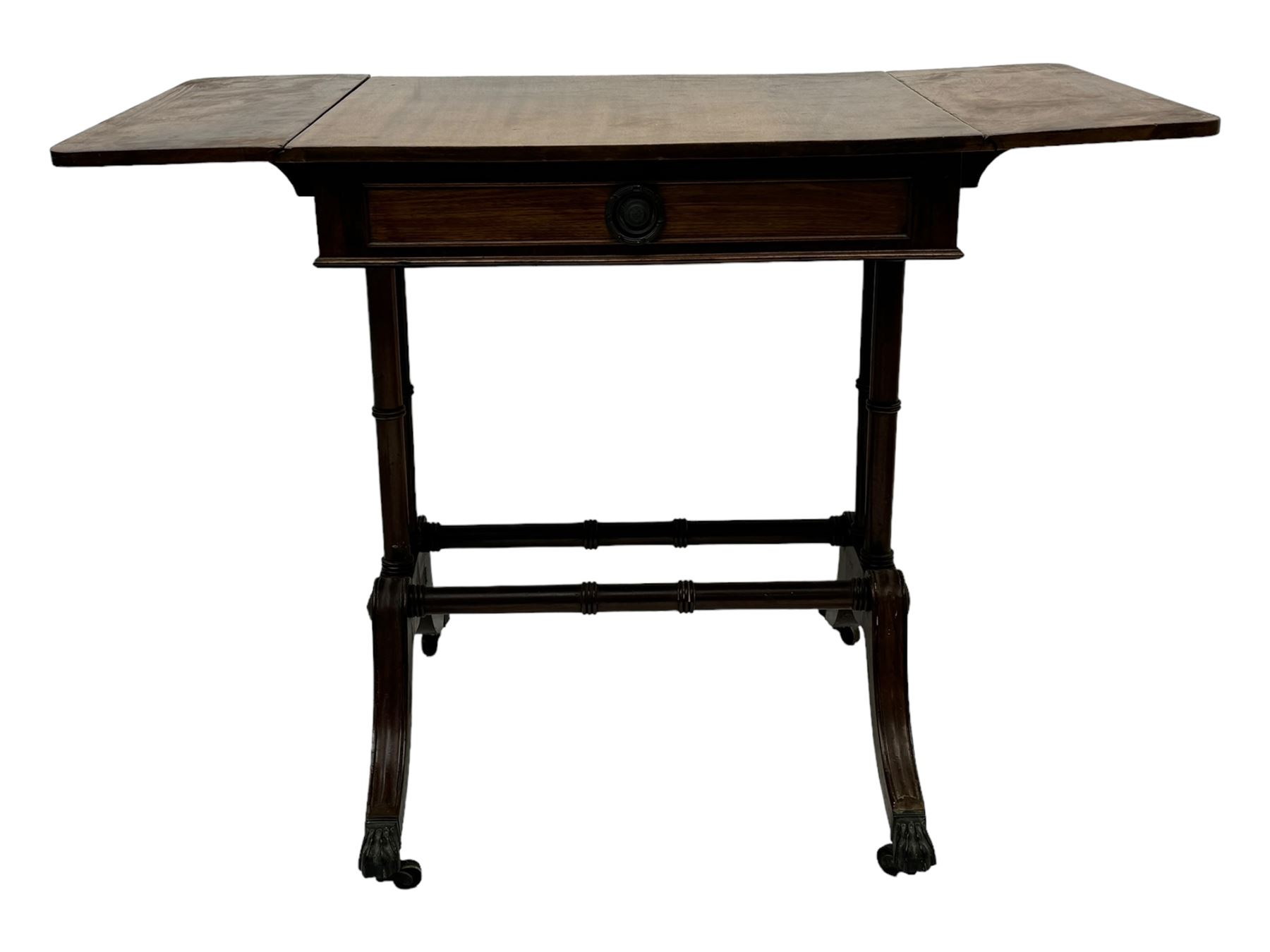 Mahogany drop-leaf sofa table, rectangular top over single frieze drawer with carved rosette handle, twin turned columns united by twin stretchers, on splayed supports terminating in paw feet with castors