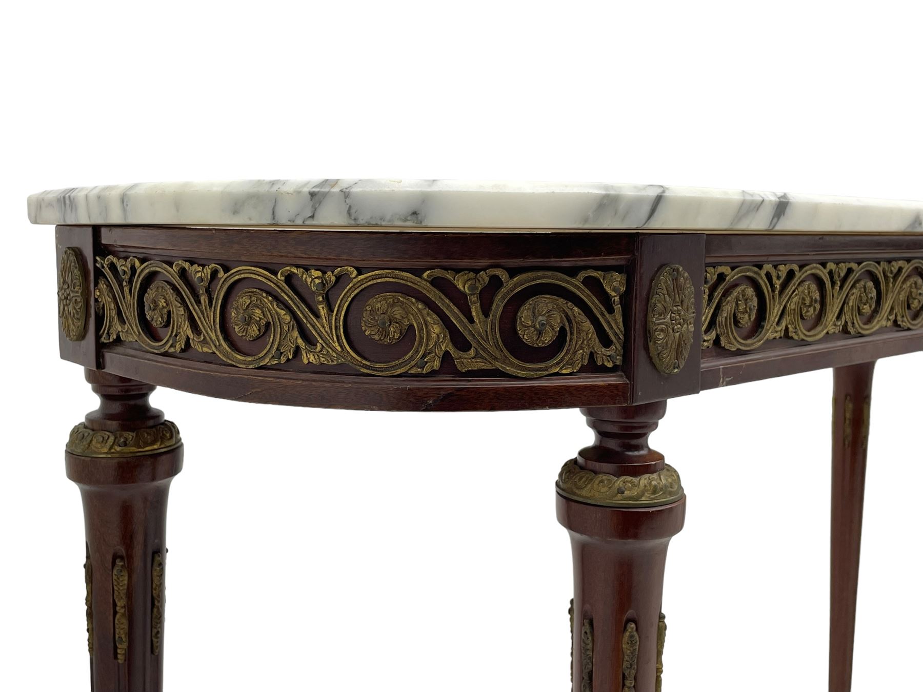 Pair of late 20th century French design mahogany console tables, D-end form with white and grey veined marble tops, the frieze rails decorated with scrolled leaf and flower head cast brass mounts, on turned and fluted supports with cast brass mounts and feet 