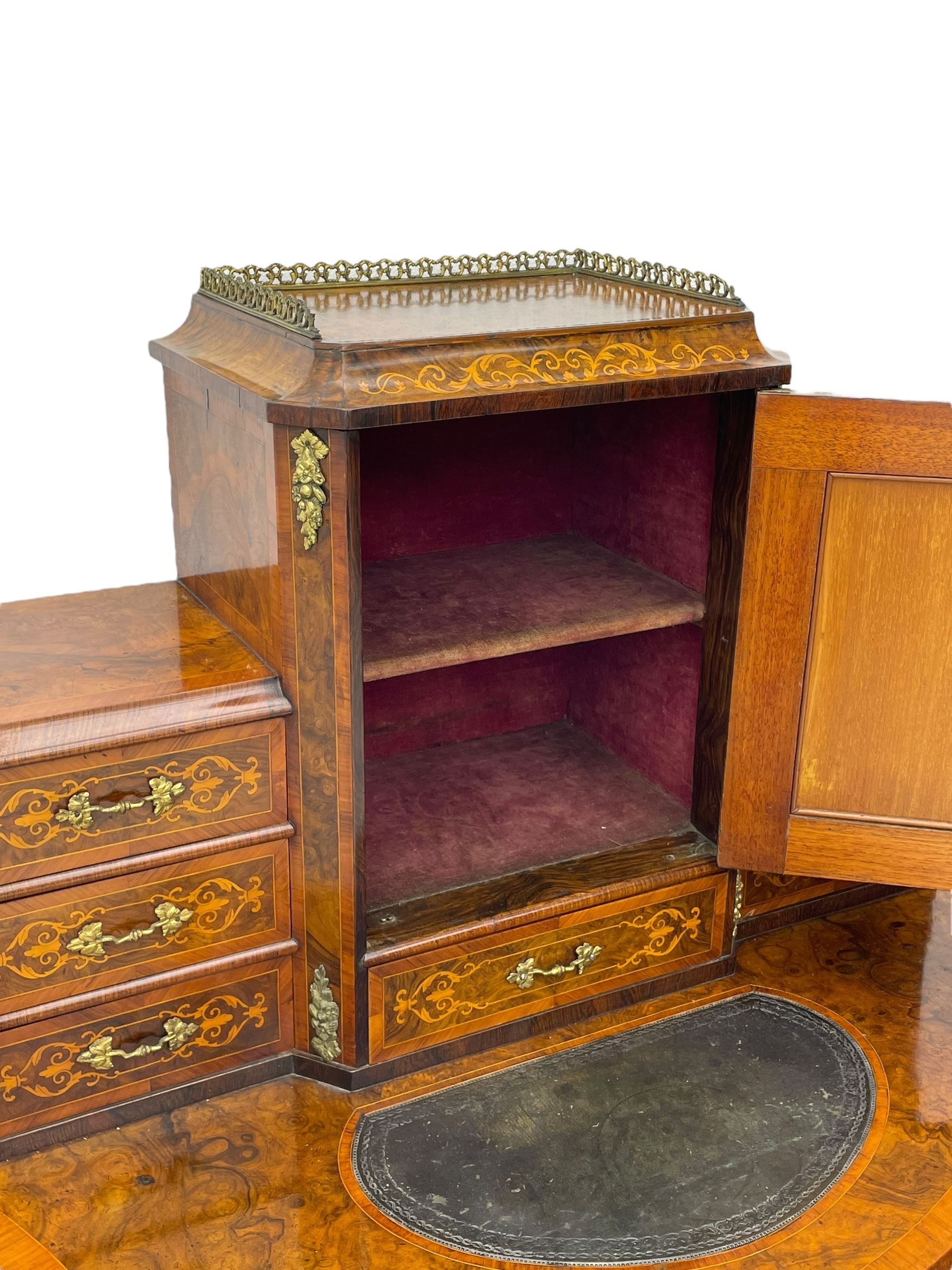 19th century French figured walnut Bonheur de Jour or writing desk, the upper section with brass gallery over mirror glazed cupboard and a combination of drawers, shaped and moulded top with leather inset and satinwood band, fitted with single drawer, on cabriole supports, inlaid throughout with scrolling foliate decoration in boxwood, ornate cast brass mounts 