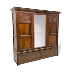 Late Victorian walnut triple wardrobe, projecting moulded cornice over central bevelled mirror door and flanking panelled doors, the top panels carved with fluted fans and stylised leaf motifs, the interior fitted with three linen slides, two drawers and hanging space, two long drawers to base, reed moulded uprights and vertical fluted horizontal rails 