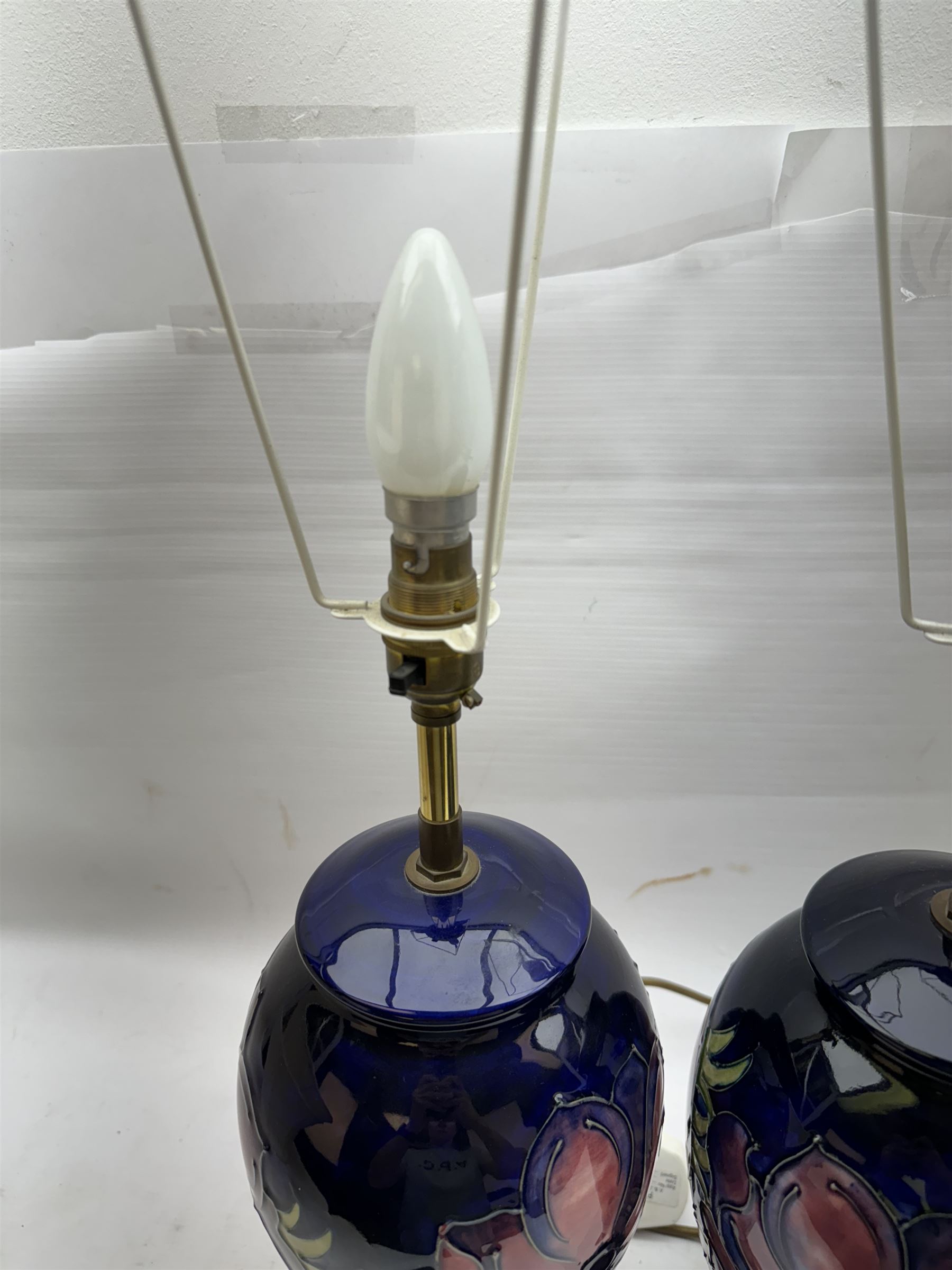 Pair of Moorcroft table lamps, in Anemone patter, upon a blue ground, with cream lampshades, H68