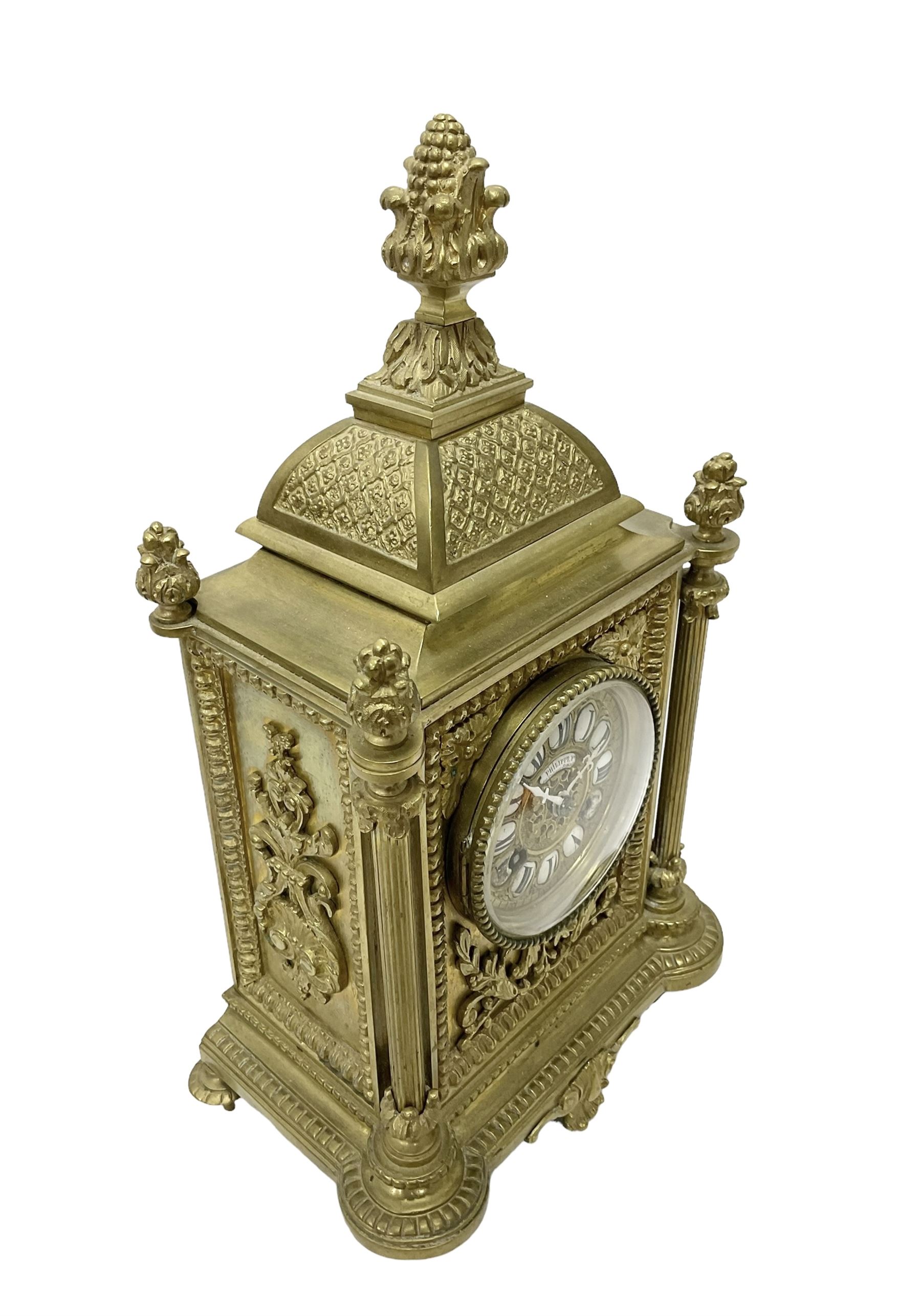 French - Brass cased 8-day mantle clock c1880, with a domed top surmounted by a pineapple finial, four reeded pilasters to the corners and raised on tapered feet, with a conforming dial with cartouche numerals, fleur-di -Lis hands and the name, Phillippe, 66 Palais Royal, Paris, twin train countwheel striking movement sounding the hours and half-hours on a bell.  With pendulum and key. 
