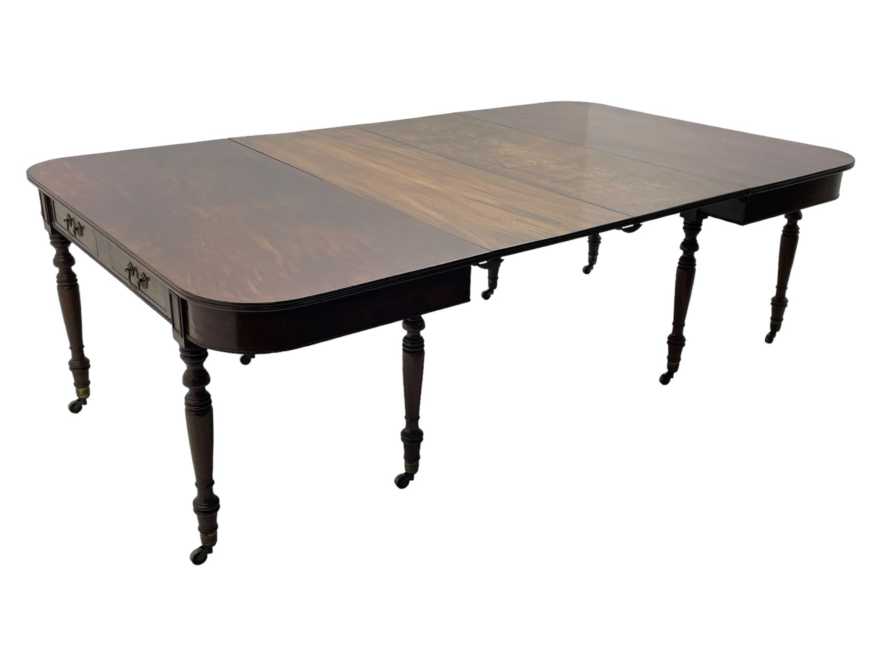 George III mahogany extending dining table, reed moulded rectangular top with rounded corners, two D-ends each fitted with two drawers, two additional leaves, on turned supports with ribbed brass cups and castors 