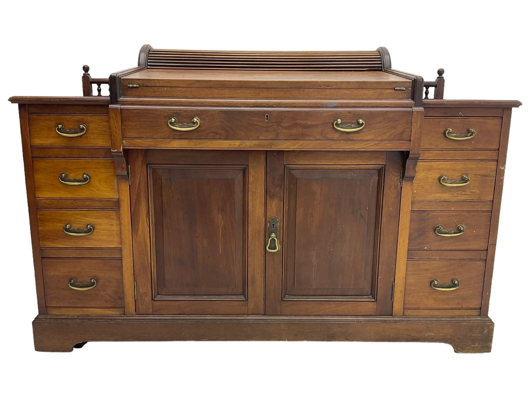 Victorian walnut clerk's desk, raised central section with tambour roll over hinged top, the interior fitted with leather inset writing surfaces, small drawers, document divisions and pen and ink stand, central drawer over double panelled cupboard, flanked by two banks of four graduating drawers, on bracket feet 