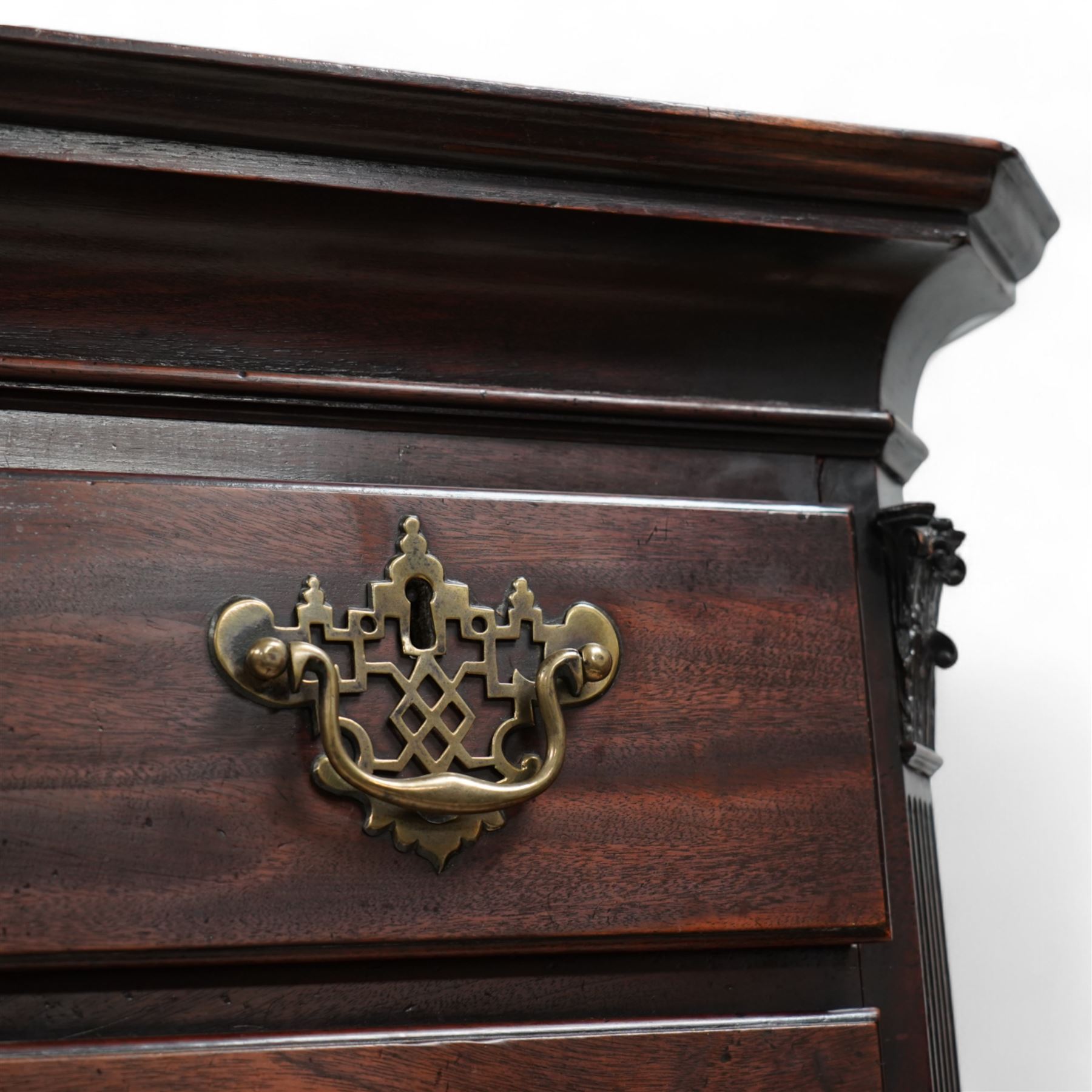 George III mahogany chest-on-chest, canted rectangular form, stepped cavetto moulded cornice, the upper section fitted with three short over three long drawers, the lower section fitted with two short over two long drawers, moulded drawer fronts with shaped and pierced handles plates and swan neck handles, enclosed by fluted corners with acanthus leaf capitals, on ogee bracket feet