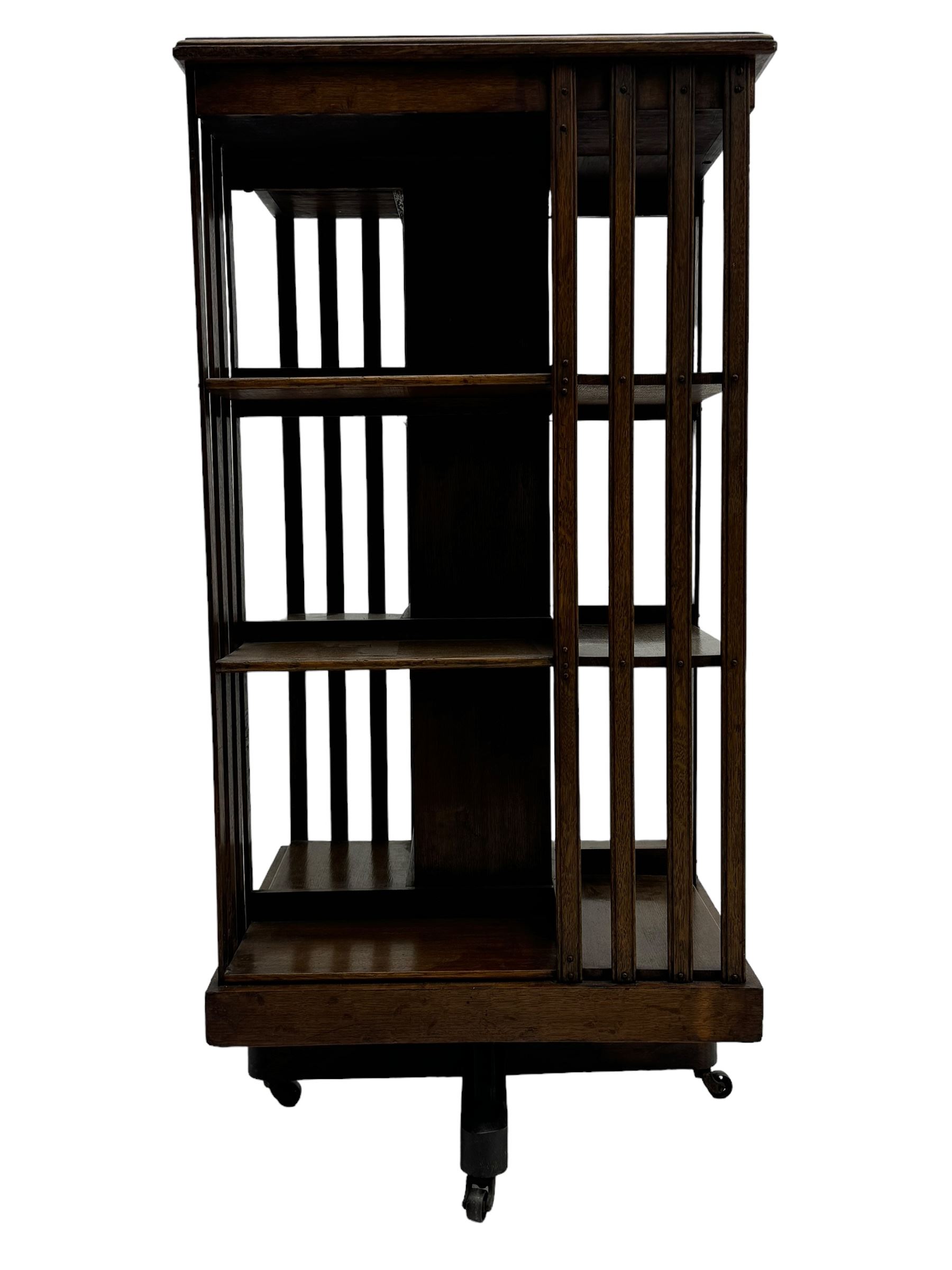 Early 20th century oak revolving bookcase, moulded square top over three tiers, with moulded vertical slats, on four spoke base with castors 