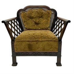 Early 20th century three-piece bergère suite - three seat sofa (W177cm, H82cm, D75cm); pair of matching armchairs (W84cm); single caned back with 'cock-pen' panelled arms, upholstered in foliate pattern fabric, blind fretwork lower frieze over square feet 