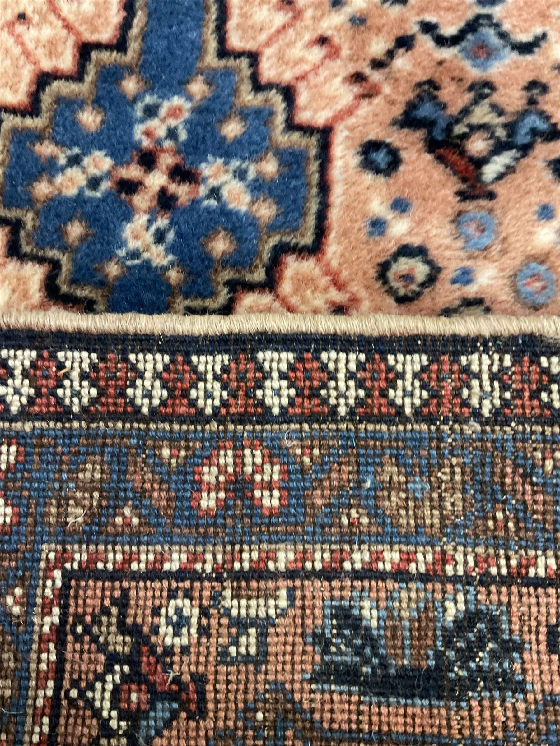 Persian prayer purple ground, decorated with three pointed buildings over tailing lozenge patterned field (111cm x 82cm); and a small Persian rug or mat, overall geometric design (81cm x 56cm)