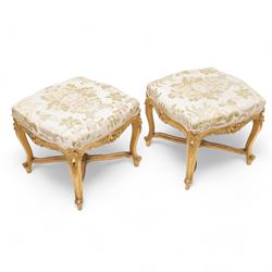 James Shoolbred & Co. (London: 1814-1934) - pair of late 19th century giltwood French design stools, shaped seat upholstered in floral pattern fabric, on shell carved cabriole supports with scrolled terminals, united by shaped X-frame stretchers, with ivorine maker's label inscribed 'Jas Shoolbred & Co.' 