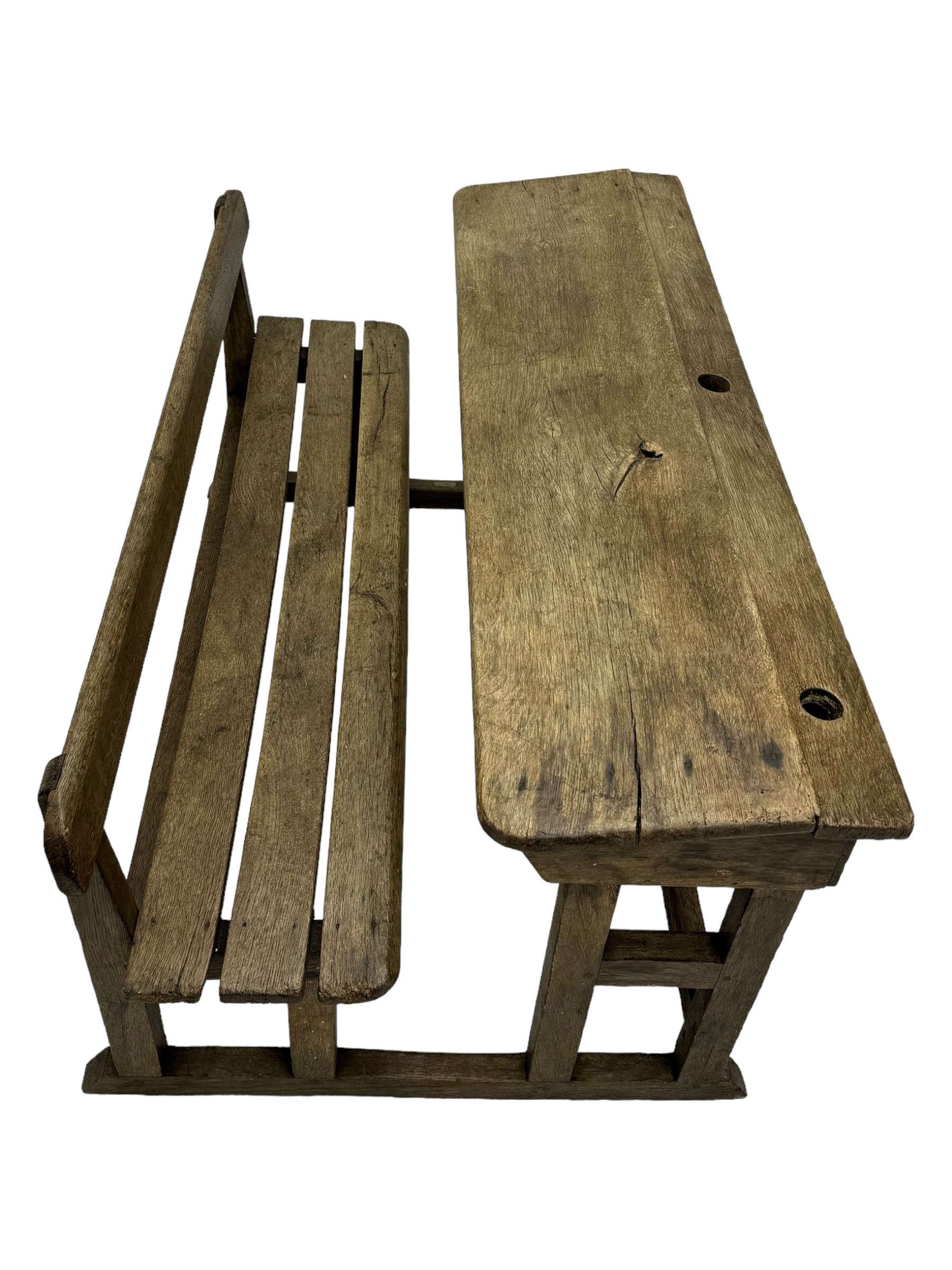 Victorian child's pine double school desk, the writing surface with two inkwells and two shelves underneath, integrated slatted bench seat raised on supports united by stretcher 