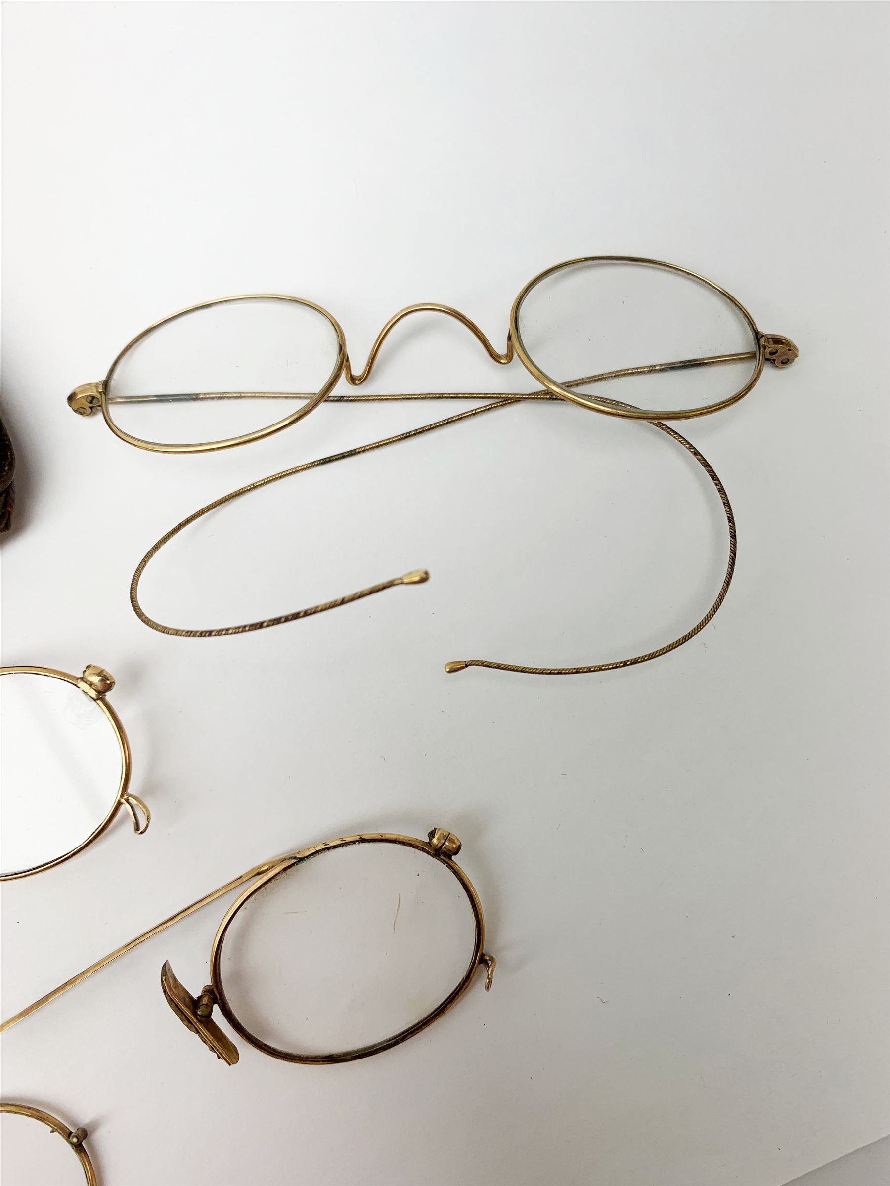 A pair of 9ct gold framed antique spectacles, marked 9 375, with case, together with a further pair, (testing around 9ct), and damaged pair (testing as gold plated). 