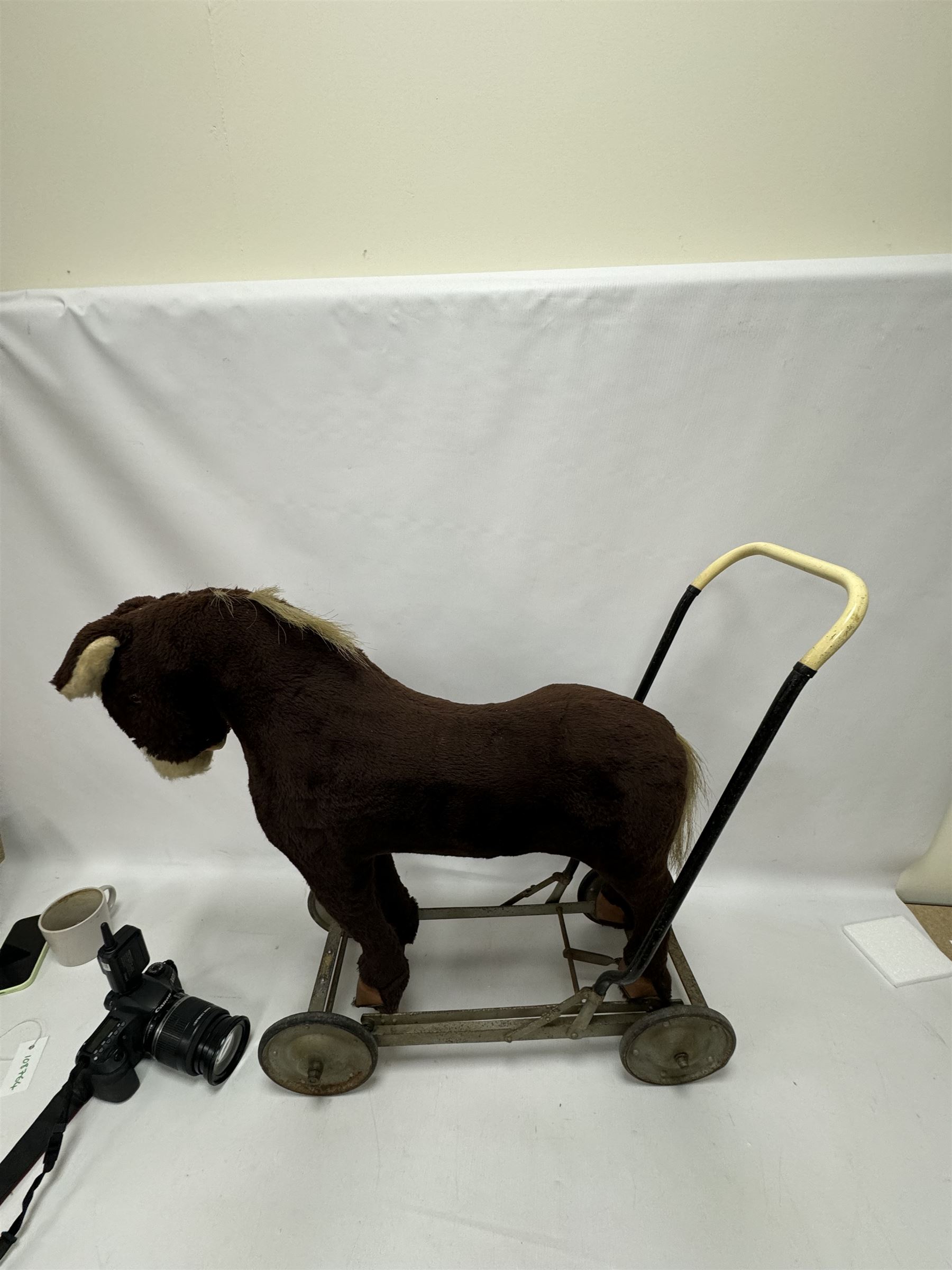 1920s/30s Panurge Pets push-a-long horse, with brown mohair body and white face, horse hair mane and tail and leather hooves, mounted upon a metal with rubber and metal wheels, including handle H71cm