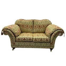 Traditional design two seat sofa, high back with scrolled arms, upholstered in beige fabric with red and green damask motifs, on castor supports (L178cm, D100cm, H89cm); matching armchair (L109cm, D89cm, H89cm)