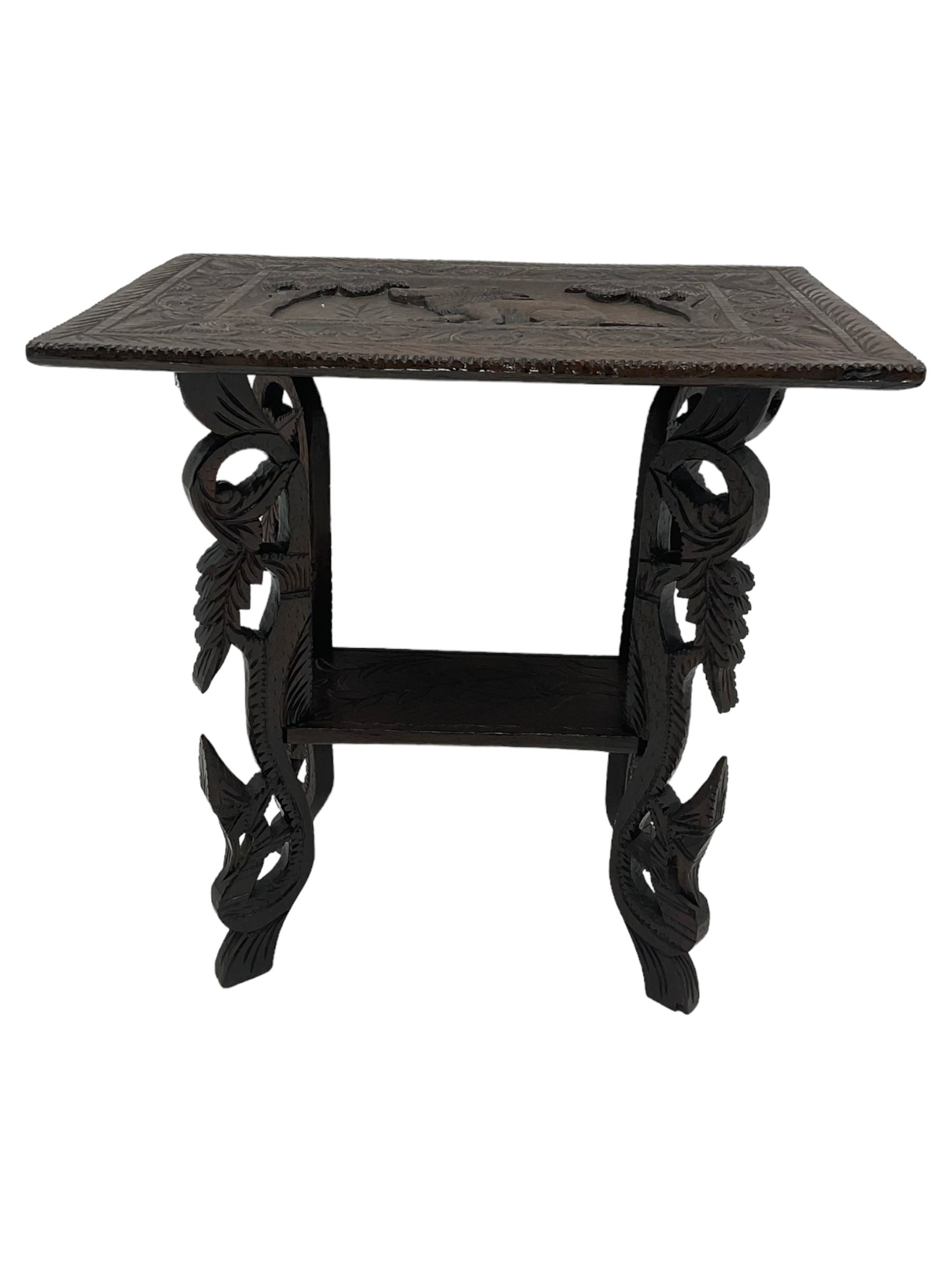 Early 20th century Anglo-Indian heavily carved hardwood table, the rectangular top carved with lion amongst trees, scrolling branch and foliage border, on leaf carved and pierced supports united by undertier 