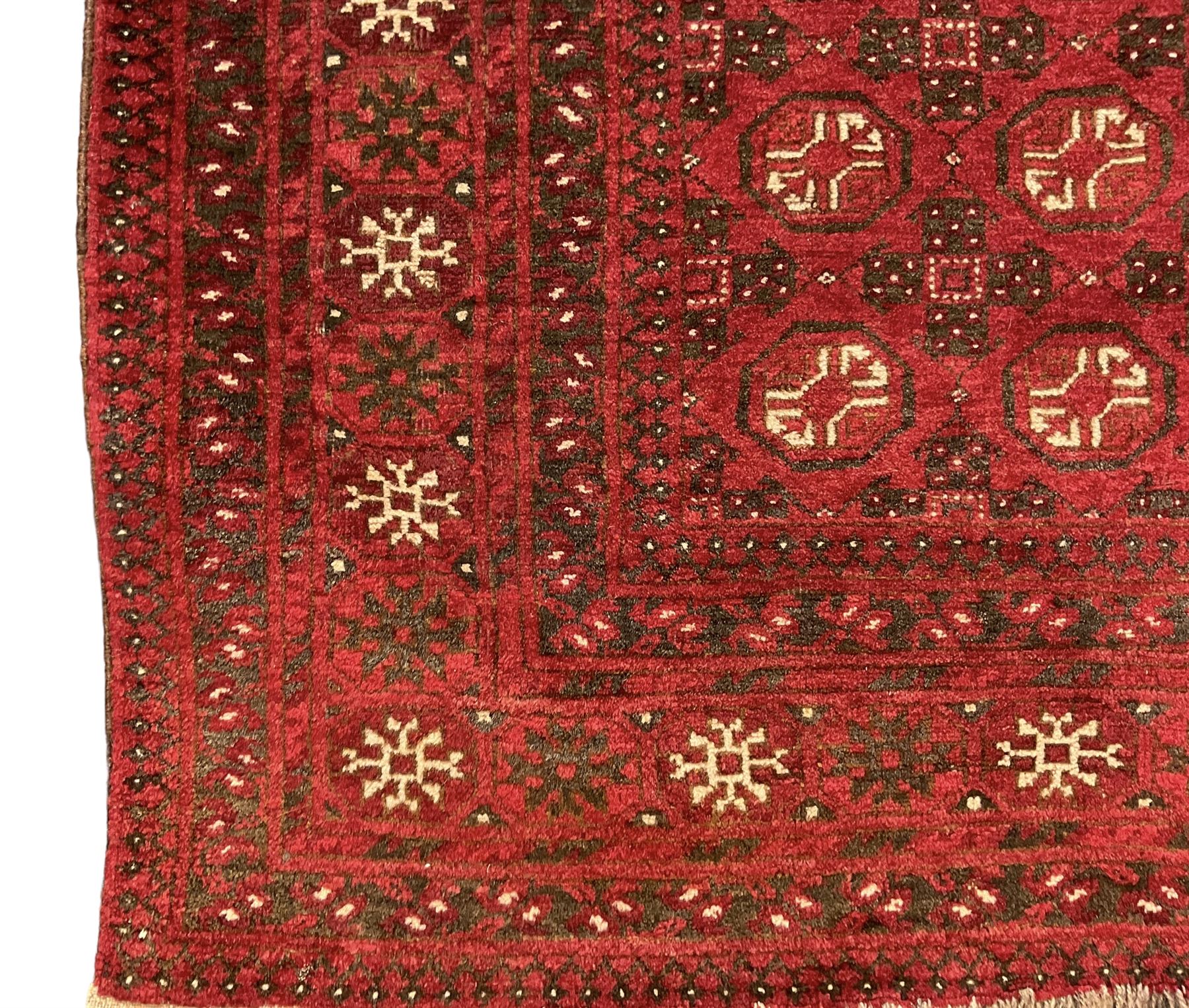 Antique Persian crimson ground rug, the field decorated with Gul motifs, the guarder border with stylised stars in ivory and dark indigo