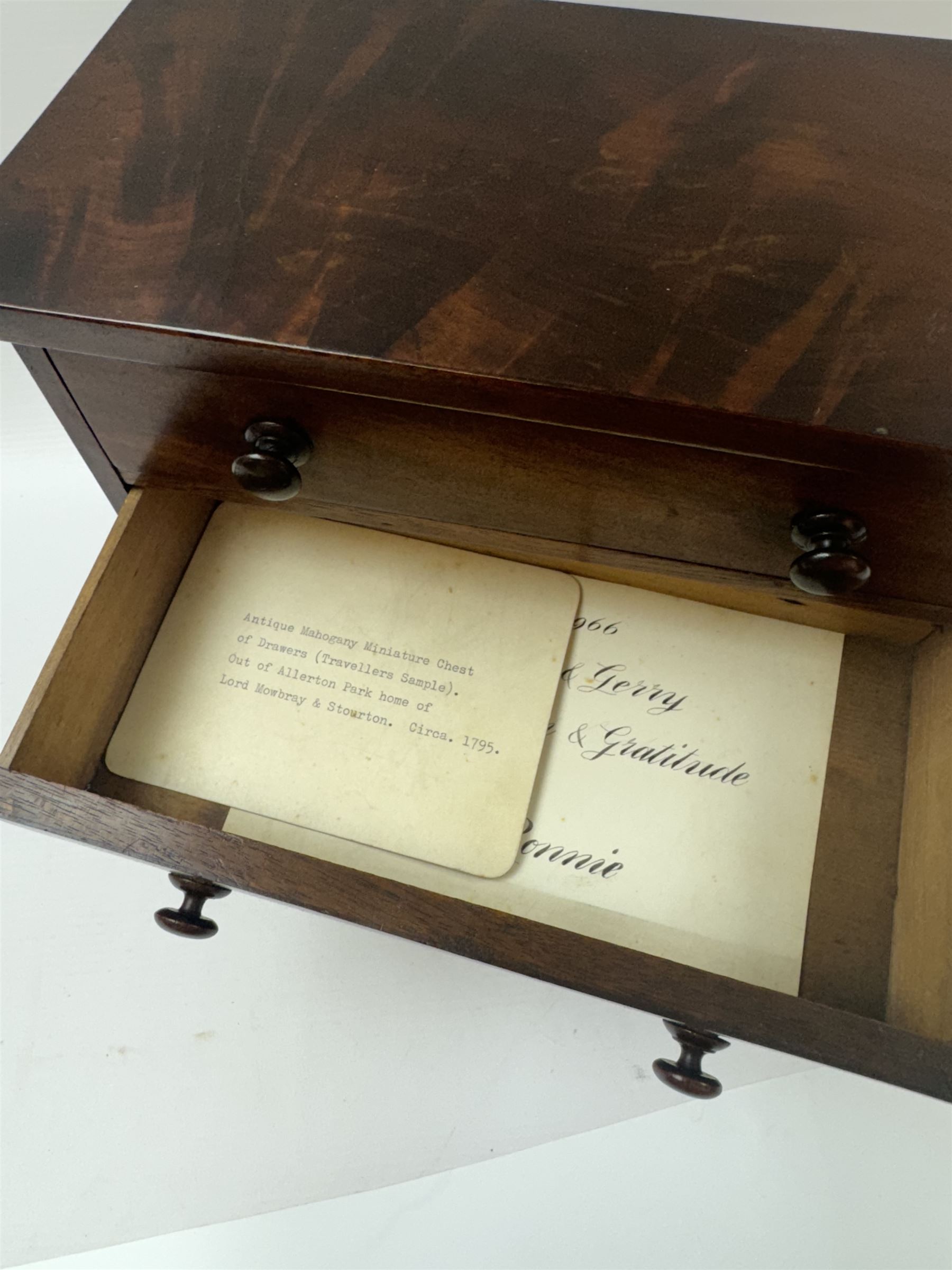 19th century mahogany miniature chest of drawers, with three graduating drawers, each with wooden handles, with inlaid shaped front and upon four bracket feet, H24cm