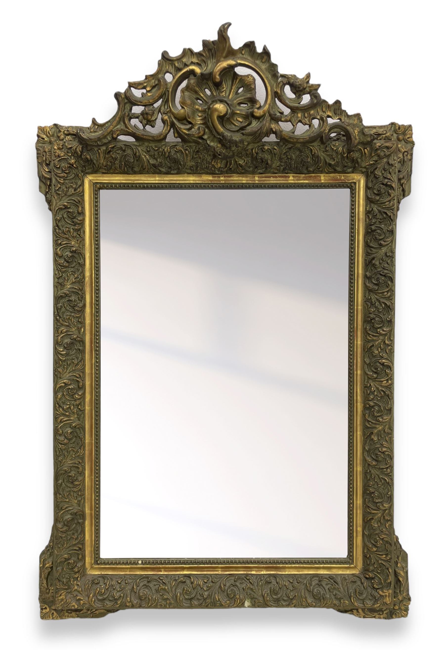 Victorian giltwood and gesso wall mirror, pierced shell cartouche pediment decorated with C-scrolls and curled leaves, moulded frame with curled acanthus leaf decoration and beaded inner slip, the corner brackets decorated with flower heads 