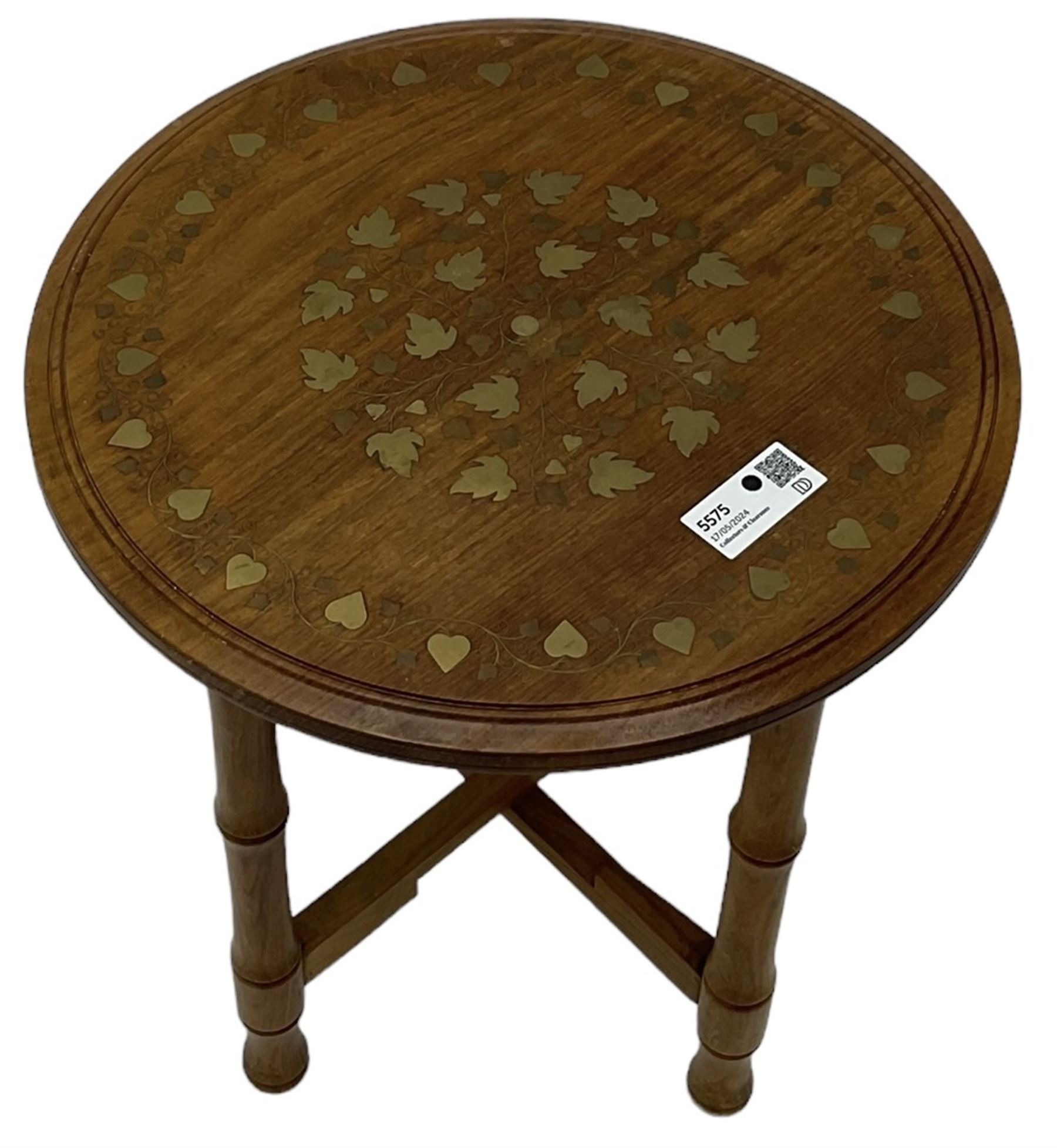 Small brass inlaid hardwood occasional table, the circular top inlaid with trailing foliate decoration, on turned folding base 