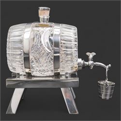 Late 19th/ early 20th century cut glass and silver plate whisky decanter by John Grinsell & Sons, of barrel form, with cork stopper and silver plate strapwork mounts, the tap suspending a bucket form measure, on trestle form support, H24cm x L24cm 