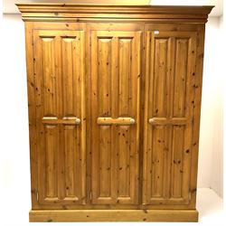 Large polished pine wardrobe, projecting cornice, three single panelled doors enclosing fitted interior including removable hanging rails, platform support 