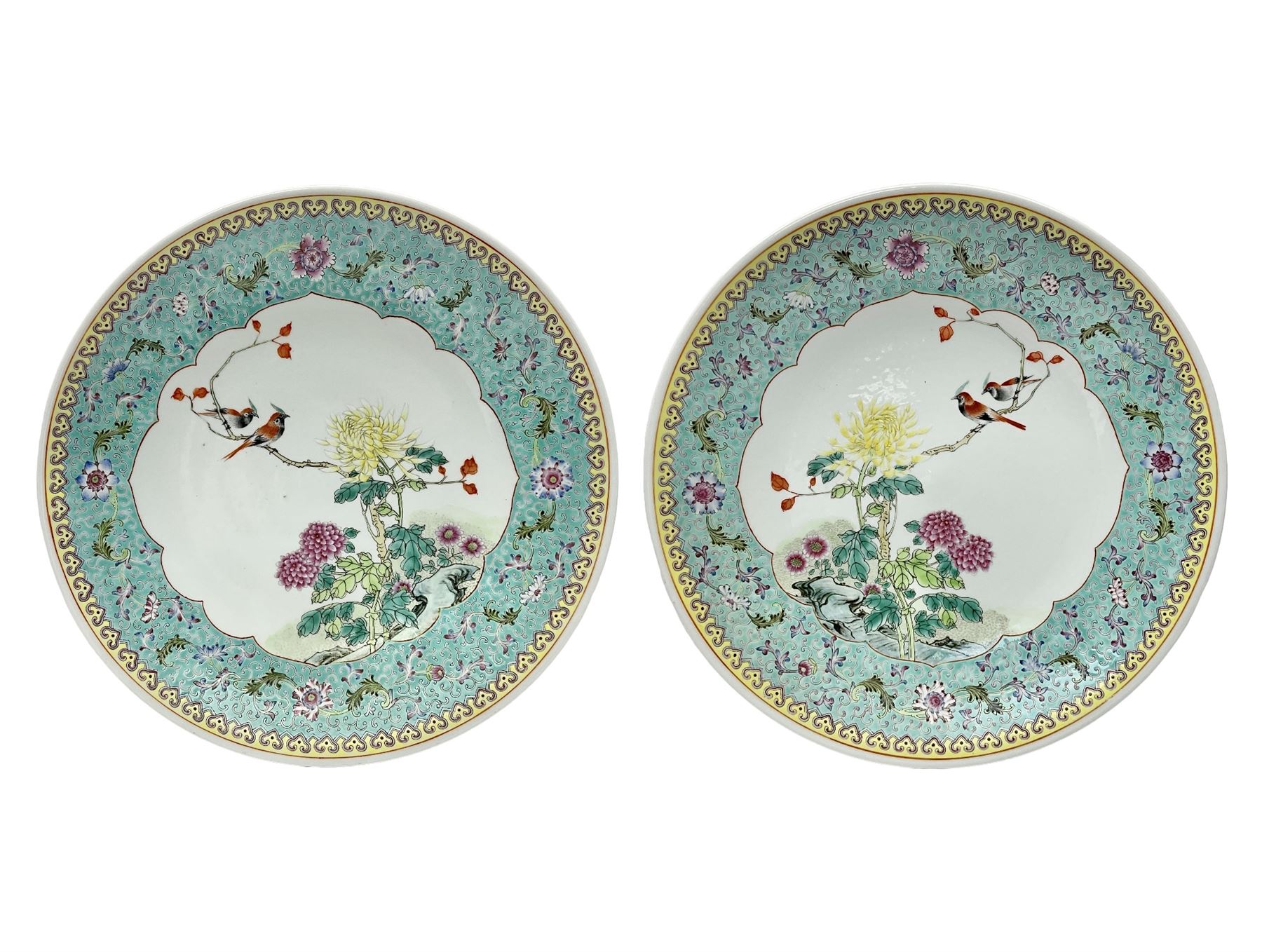 Pair of mid 20th century Chinese Qianlong Nian Zhi Famille Rose chargers, each decorated with two red crested birds perched upon a branch above blossoming pink and yellow peonies and chrysanthemums, within a turquoise border decorated with stylised flowers and scrolls, and yellow outer border, each with Qianlong Nian Zhi mark beneath, D33cm