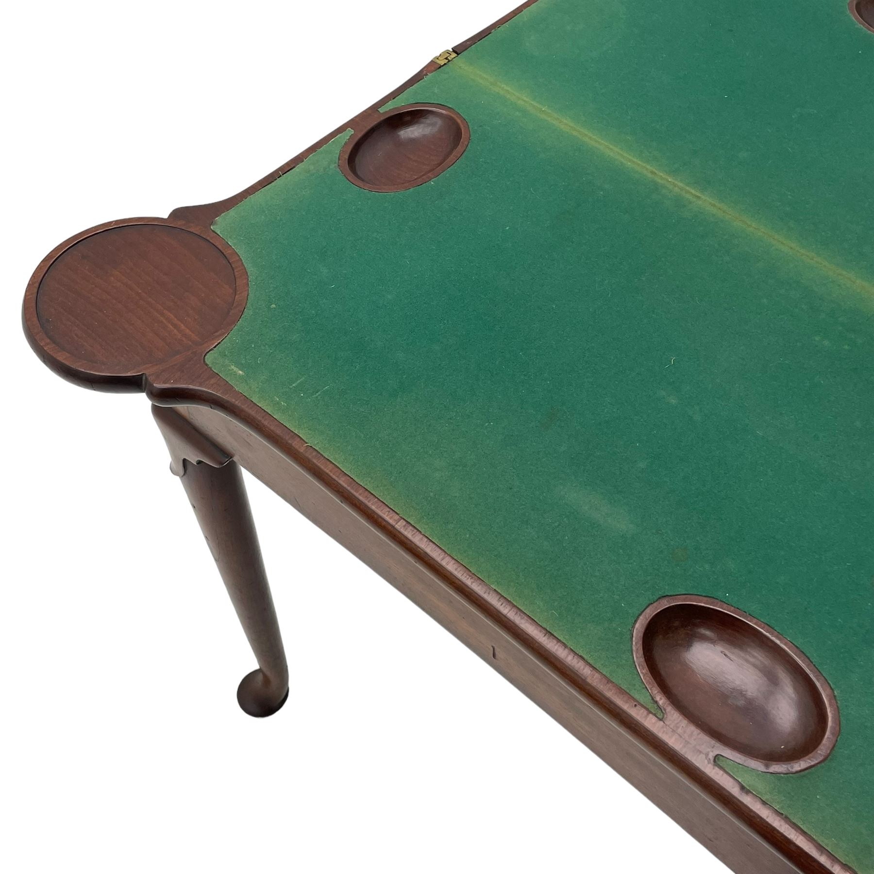 George III mahogany games table, the rectangular fold-over top with extending stepped rounded corners, opening to reveal baize lined interior with sunken counter wells, concertina action base, on lappet cabriole supports