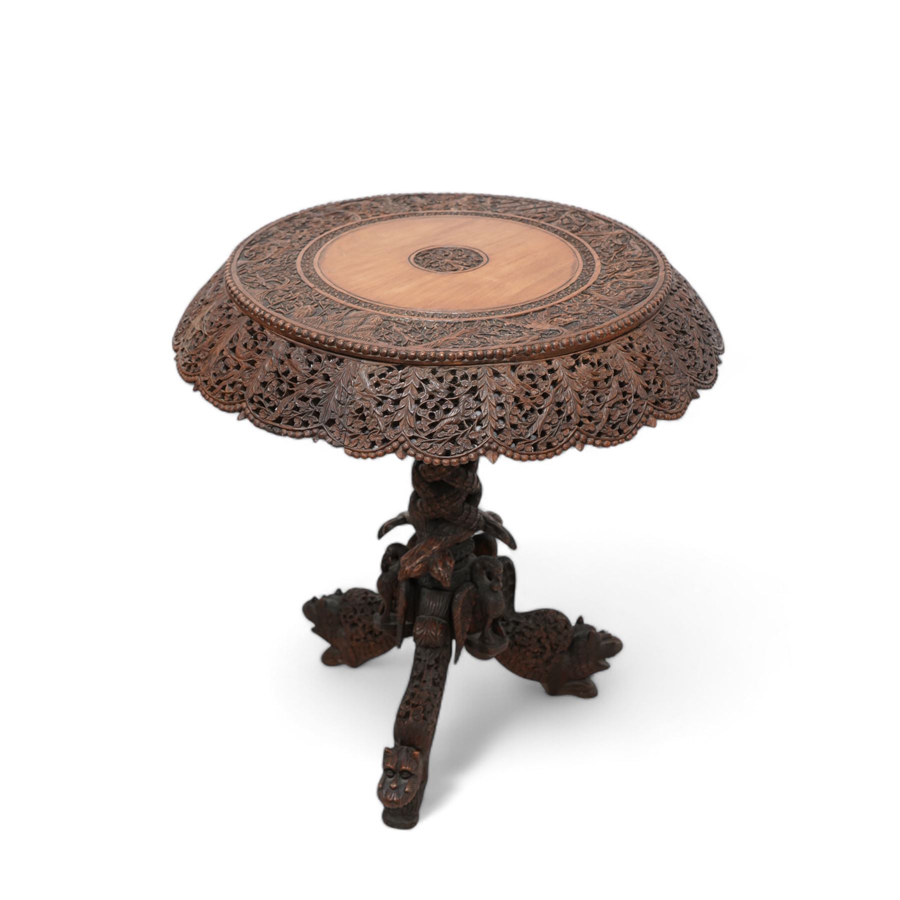 Early 20th century Anglo-Indian hardwood tripod table, circular top profusely carved and pierced with trailing foliate branches, on column carved with twisted scaled snake-like creatures, on three out-splayed supports carved with masks