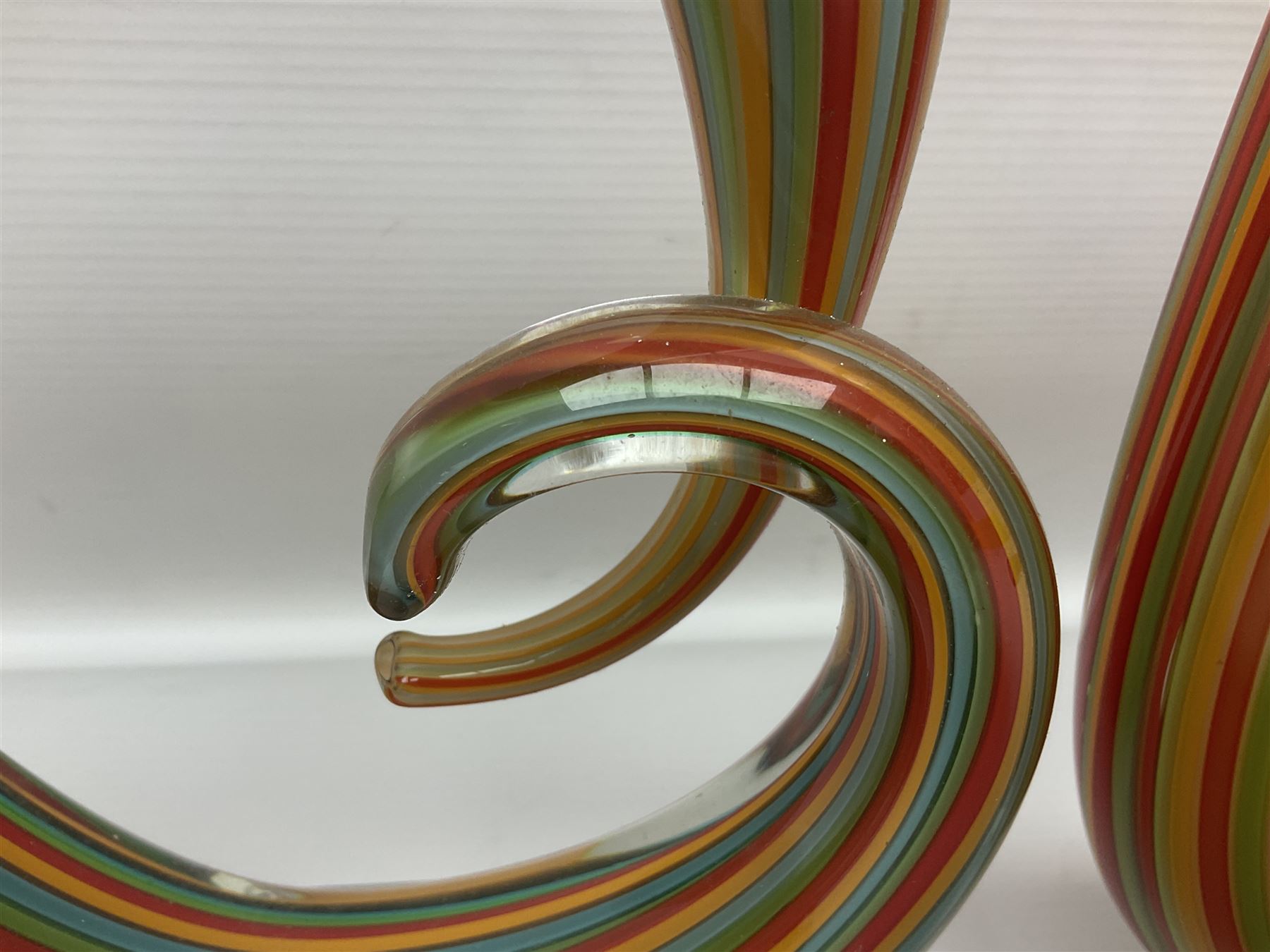 Three art glass sculpture, coiled form with multicolour stranded, upon clear glass plinth, unsigned, largest H27cm