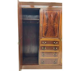 Edwardian inlaid mahogany combination wardrobe, projecting moulded cornice over figured frieze with satinwood banding, the central section fitted with cupboard over four long drawers, figured matched veneers and satinwood bands, flanked by two full height compartments enclosed by bevelled shield shaped mirror doors, satinwood fan inlaid spandrels, on moulded skirt base 