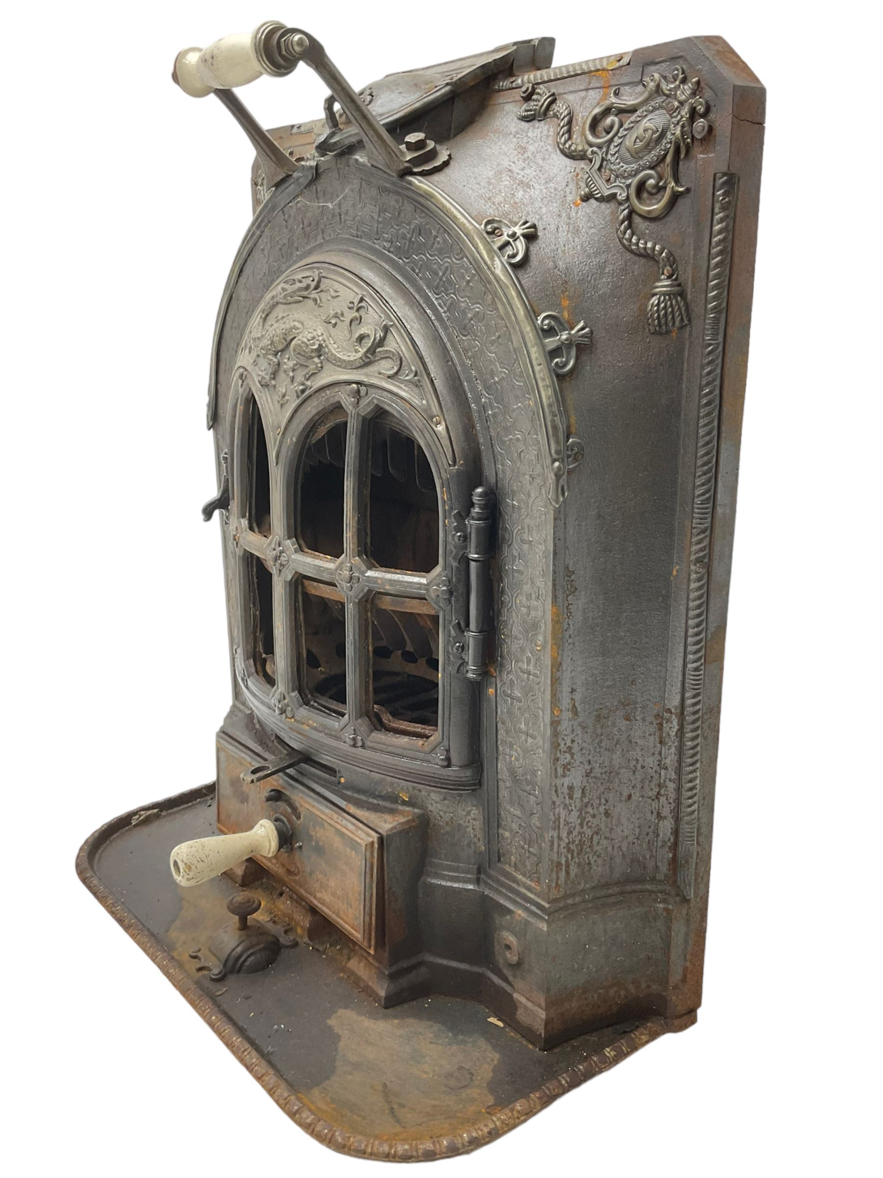 La Salamandre - early 20th century cast iron wood burning stove, decorated with salamander and cartouche motifs, fitted with porcelain handle, on rear castors 