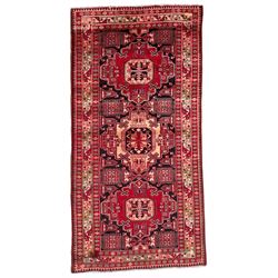 Persian Hamadan indigo and crimson ground rug, the field filled with three shaped medallions, overall geometric design, decorated with sandikli and hac motifs, geometric main border with repeating hooked motifs, within guard stripes decorated with small flower heads, outer crenelated fence band 