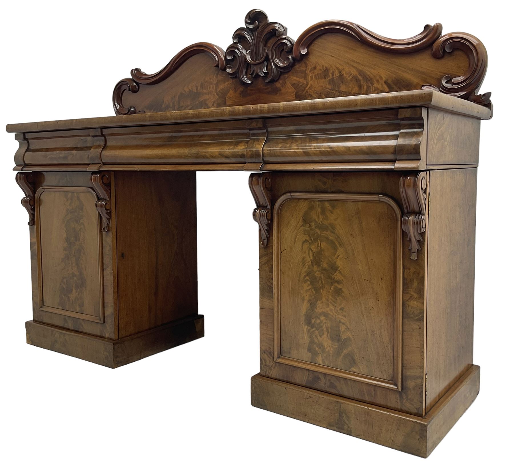 Victorian mahogany twin pedestal chiffonier, raised back with decorated with scrolling foliate motifs, fitted with three cushion drawers, the arched panelled pedestals enclosing shelves and sliding trays