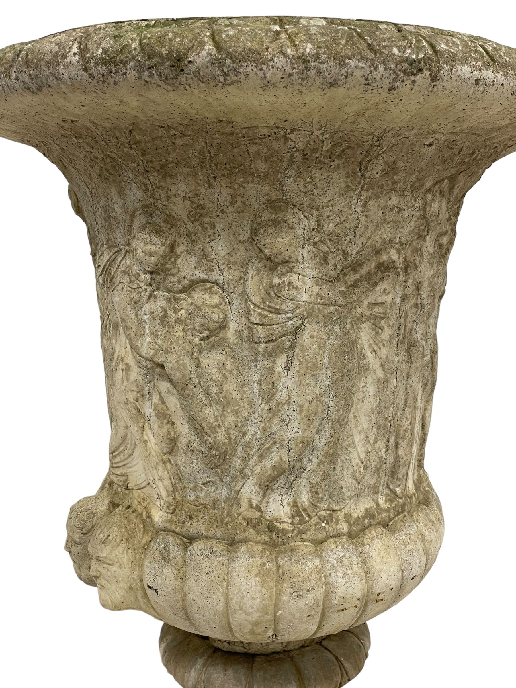 Cast stone Campana shaped urn, decorated with festival scenes over gadrooned underbelly, circular foot on square base