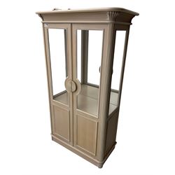 Contemporary display cabinet, moulded cornice above glazed panelled doors with central carved sunburst handles, mirrored back interior with lighting, lower enclosed storage compartment, raised on plinth base