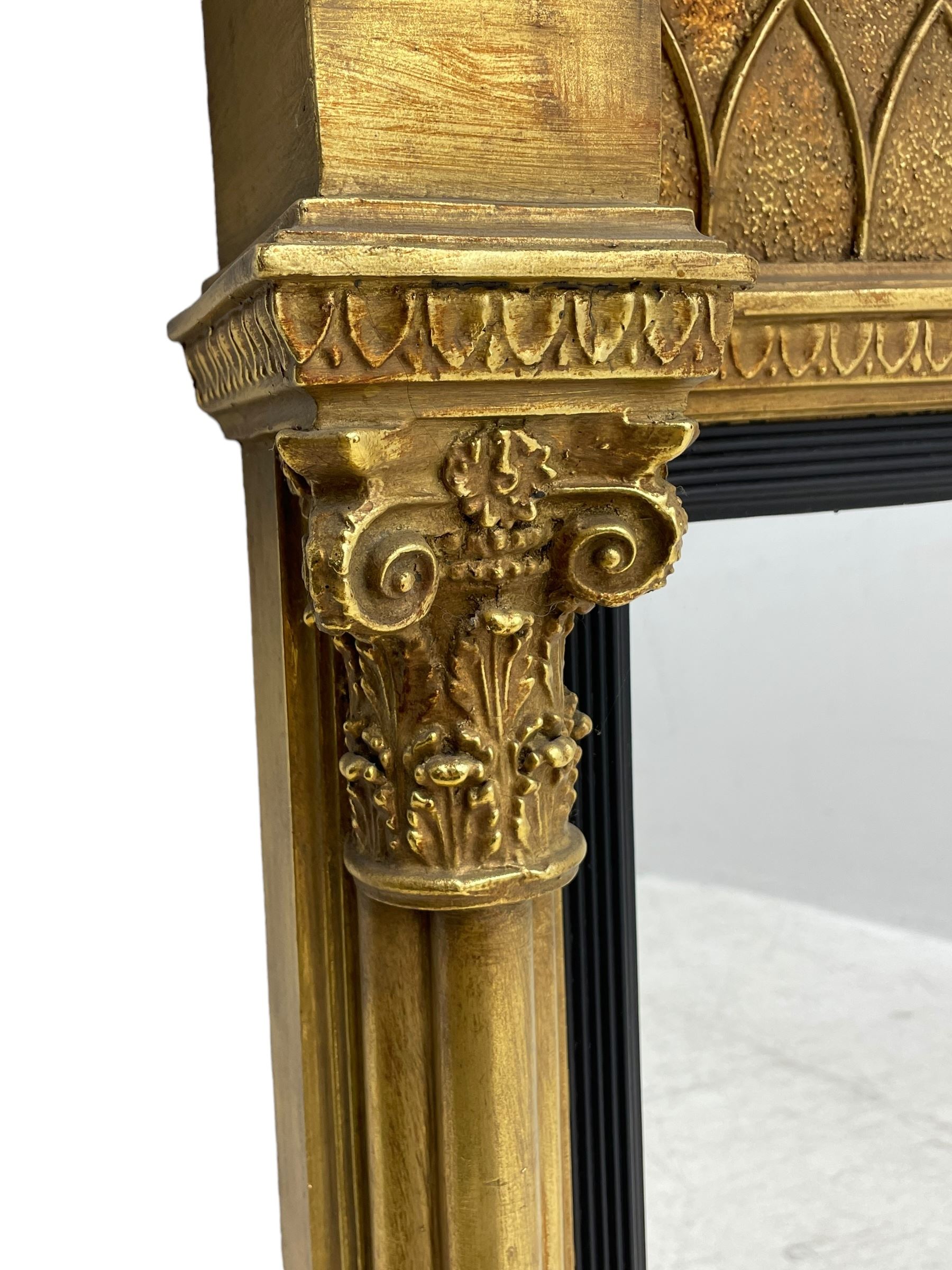 Regency design giltwood overmantel mirror, projecting cornice over pointed arcade frieze and foliate moulded upper edge, plain mirror plate within reed moulded ebonised slip, flanked by cluster columns with acanthus and scroll decorated Composite order capitals 