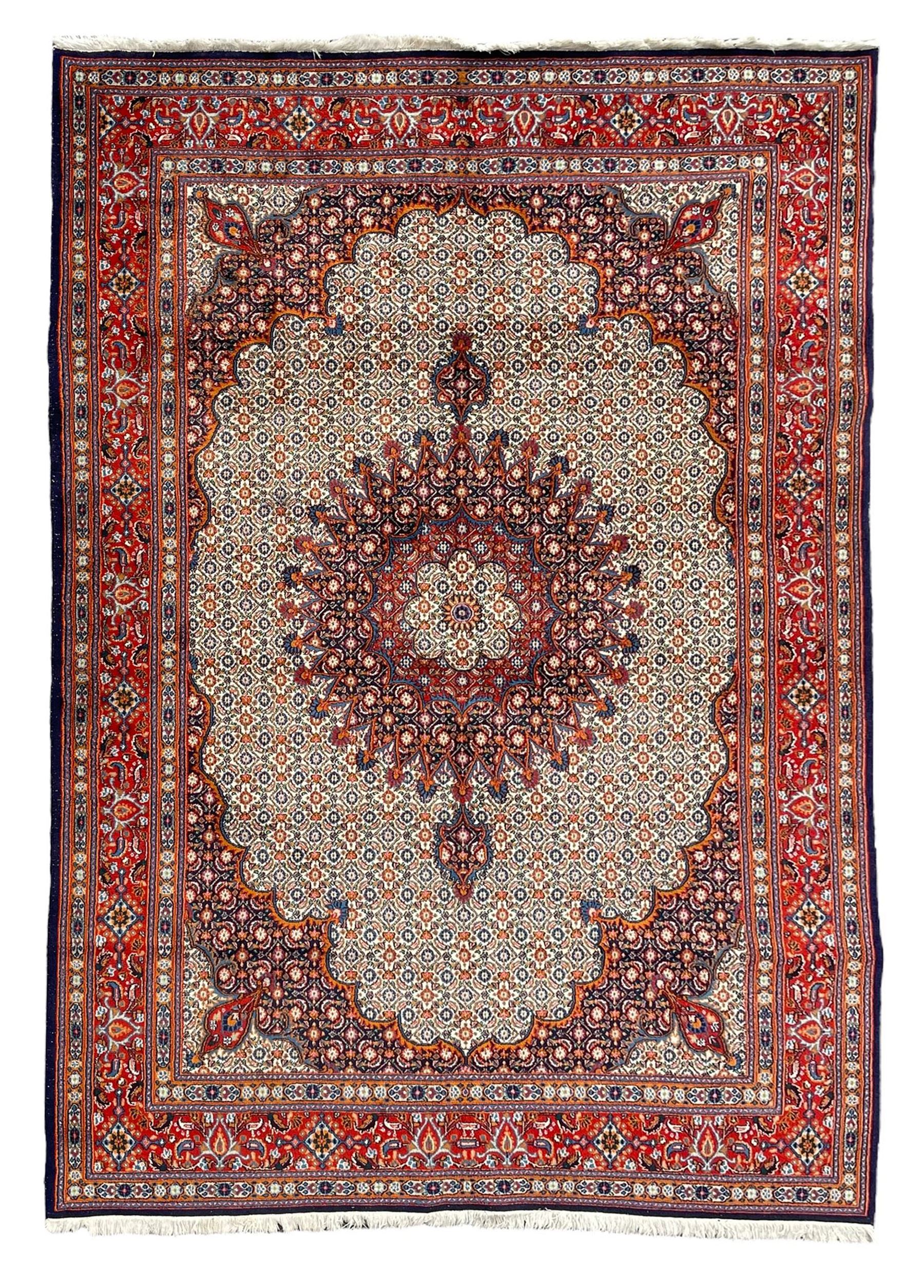 Persian Bidjar ivory and indigo ground rug, large central rosette medallion surrounded by floral herati motifs, crimson ground border decorated with repeating palmettes, within guard stripes decorated with small flower head motifs 