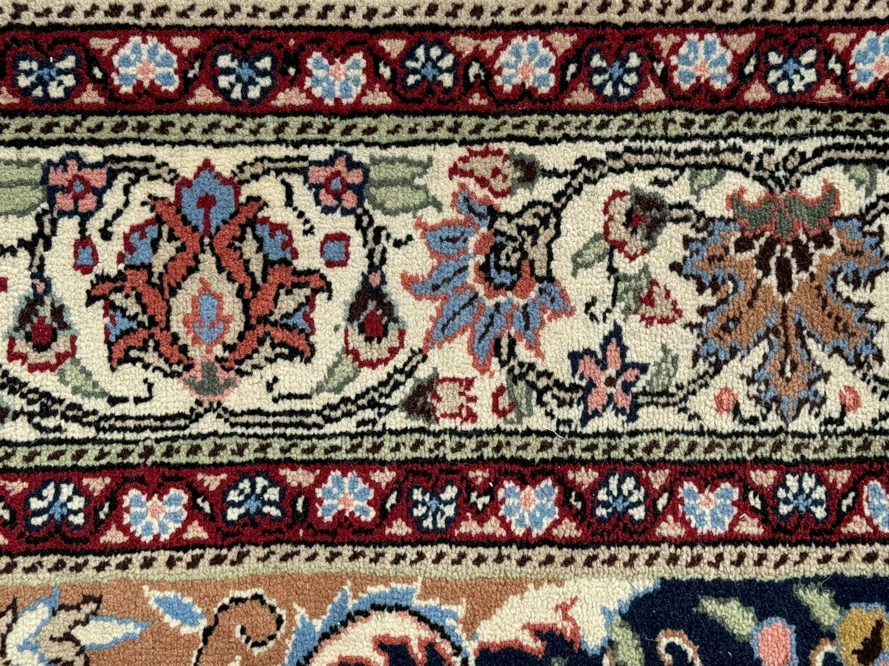 Indo-Persian indigo ground rug, the floral design peach medallion surrounded by trailing and interlaced branches and flower heads, the main border decorated with repeating stylised plant motifs within floral guard stripes 