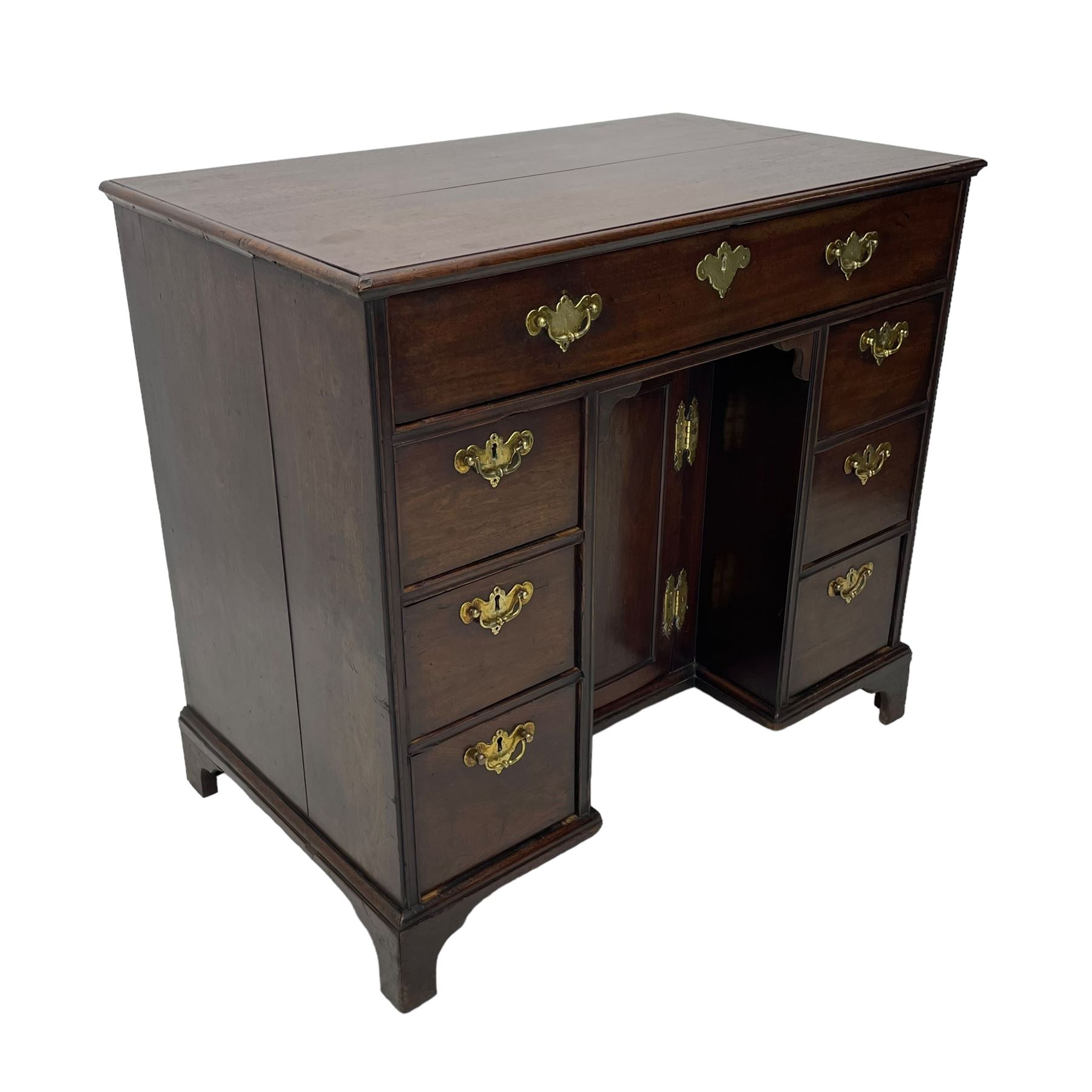 George III mahogany kneehole desk, moulded rectangular top over one long drawer, six short drawers and recessed panelled cupboard, cock-bead moulded frame, fitted with shaped brass handle plates with engraved decoration, on bracket feet 