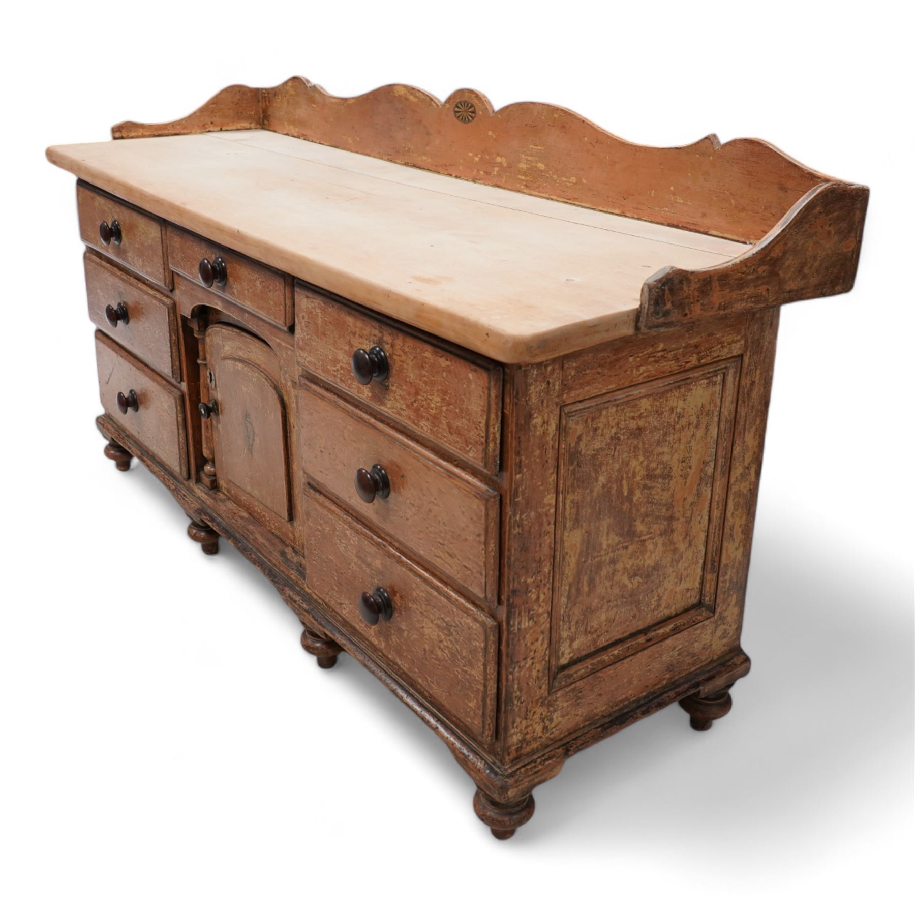 Victorian scumbled pine and sycamore dresser base, the sycamore top framed within shaped gallery, fitted with seven drawers and central cupboard enclosed by half columns mounts, on turned feet 