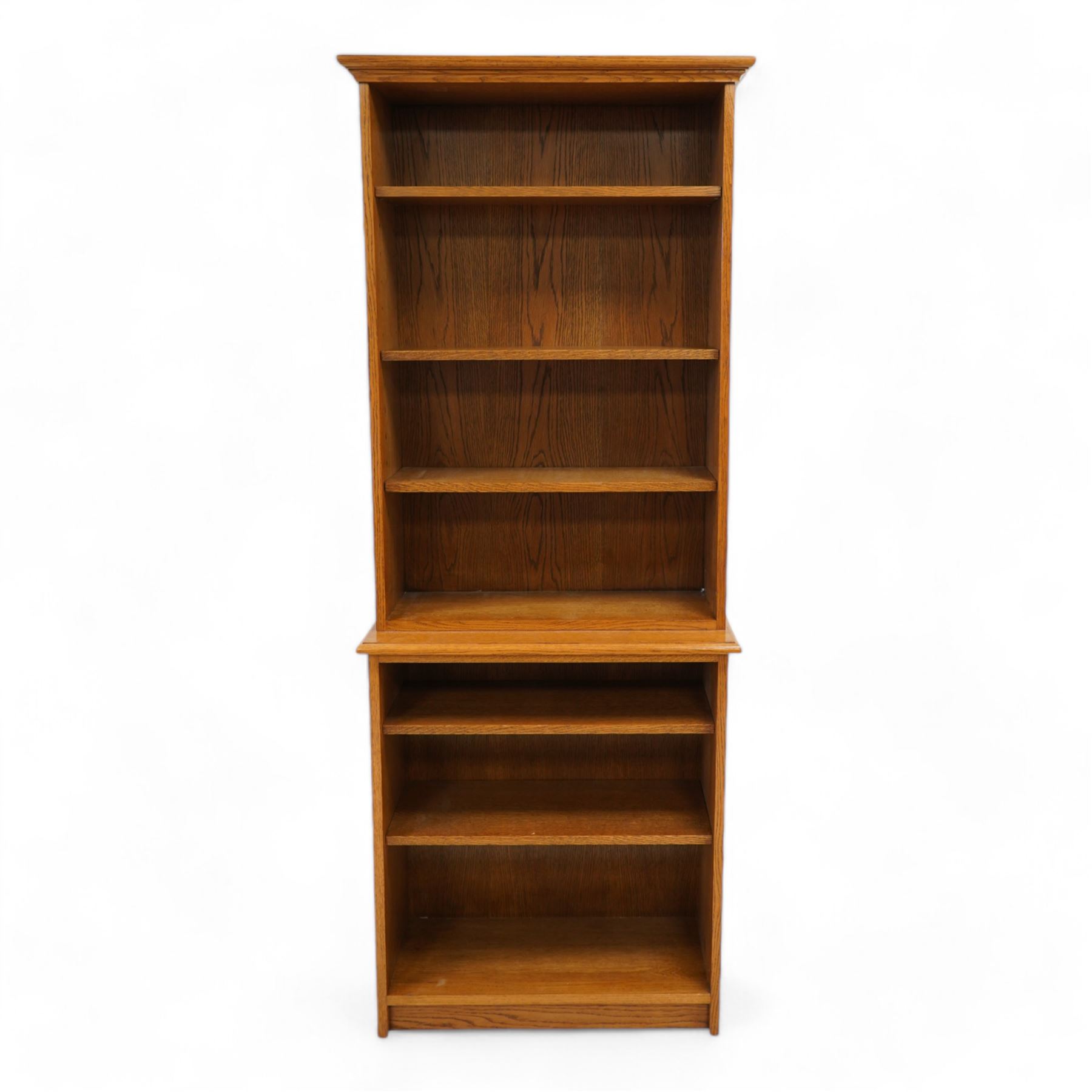 Light oak two-sectional bookcase, projecting moulded cornice over five adjustable shelves, carved with oak leaf motif 