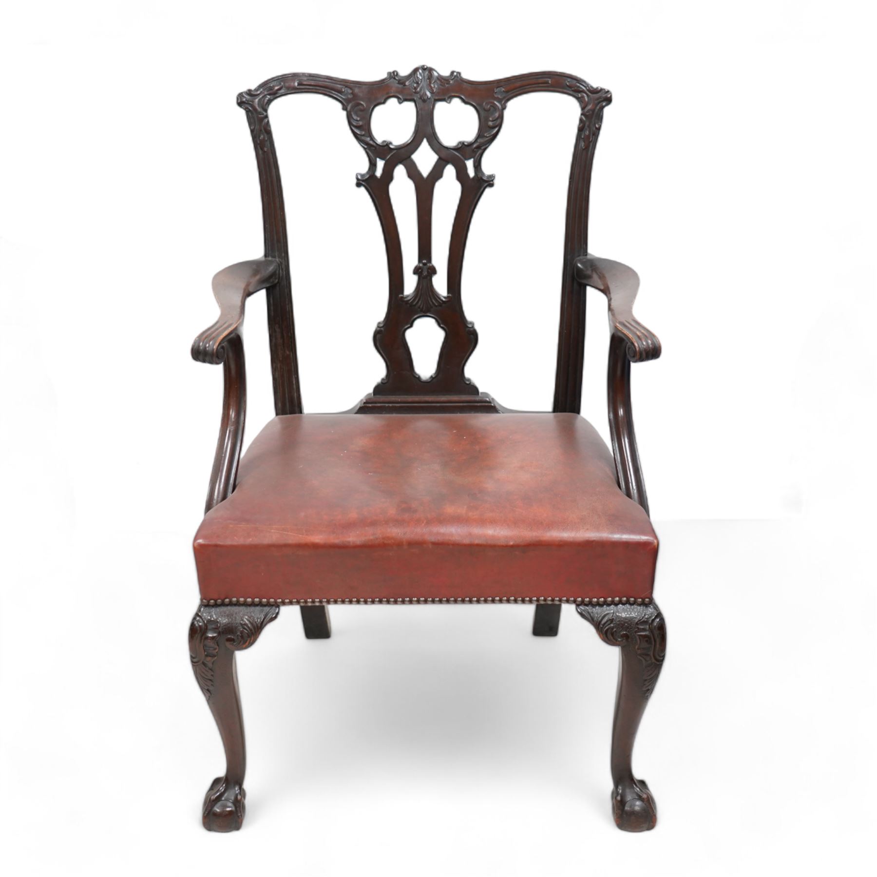 Early 20th century pair of Chippendale design mahogany elbow chairs, shaped cresting rail carved with foliate cartouches and scrolled leaves, pierced and interlaced Gothic splat, shaped arms with scroll carved terminals, leather upholstered seat with stud band, cartouche carved cabriole supports with ball and claw feet 