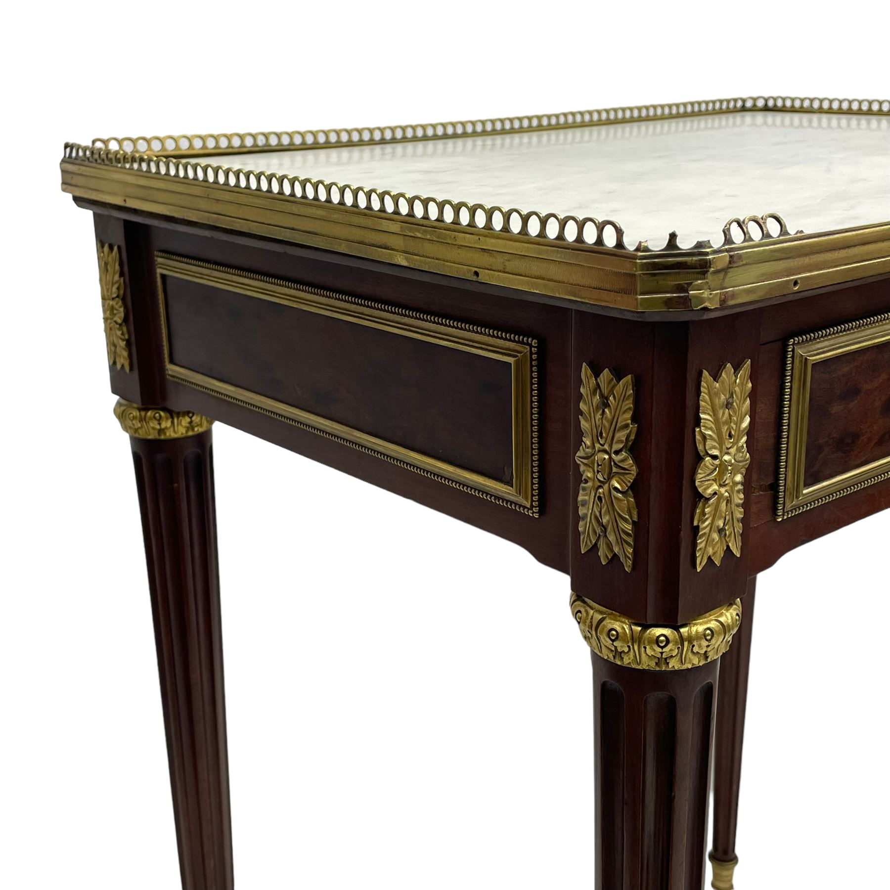 Late 19th century French figured plum pudding mahogany side table, canted rectangular white marble top with raised gilt metal gallery, fitted with a single frieze drawer, central extending floral cast ormolu escutcheon and applied moulded edging, on tapering turned and fluted supports with brass cups and castors, decorated with cast foliate mounts and foliate cast collars 