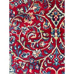 North west Persian Sarouk crimson ground rug, central floral medallion surrounded by scrolling branches decorated with foliage and stylised plant motifs, the main border decorated with repeating scrolling design with floral motifs, within guard stripes 