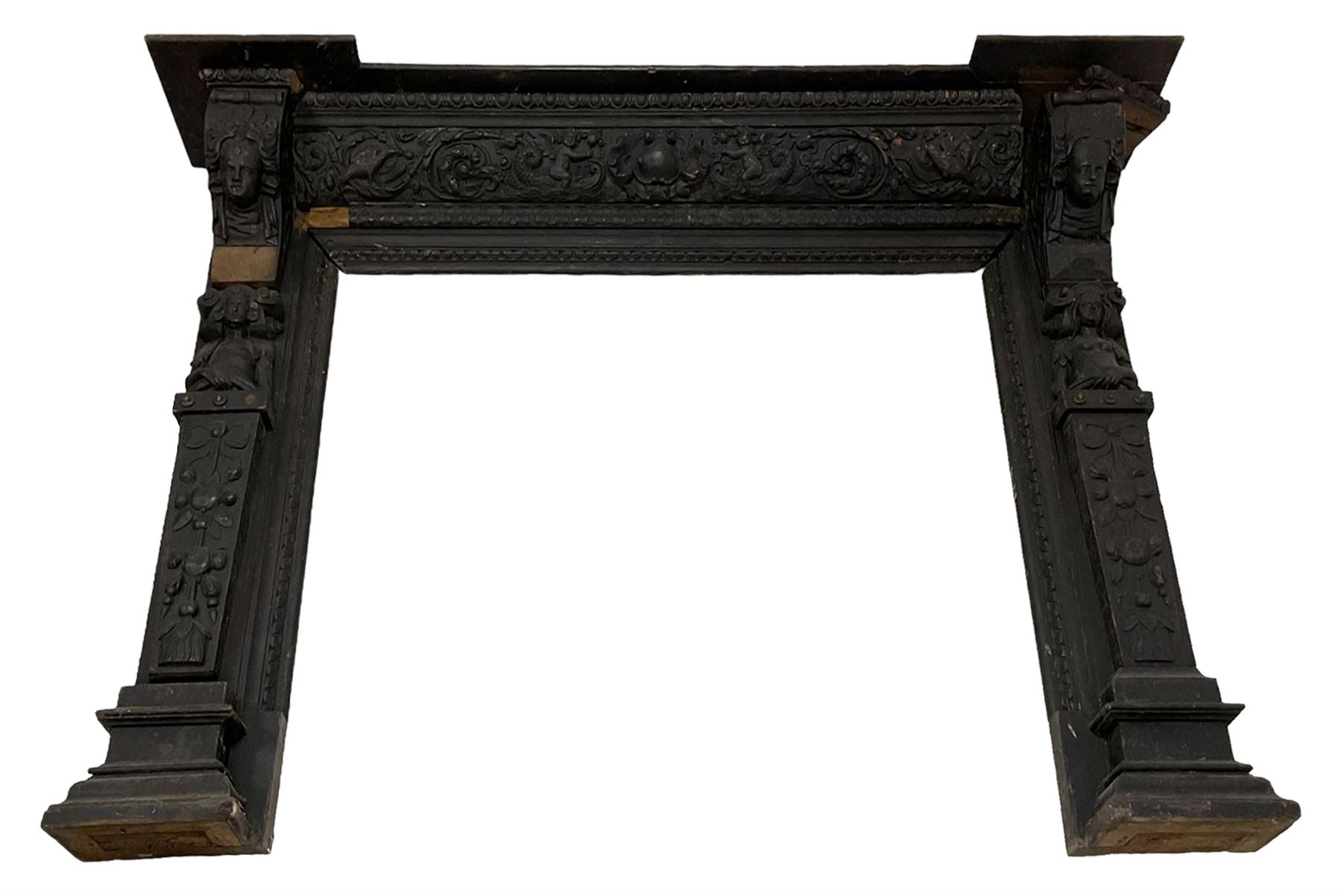 19th century Elizabethan design carved oak fire surround, reverse break-front lintel over egg and dart moulded upper edge, the ovolo-moulded frieze carved with scrolling leafy branches, central cartouche and putti riding dolphins, the uprights carved with female masks over carved busts, square tapering pilasters carved with ribbon tie over trailing fruit, on stepped moulded base 