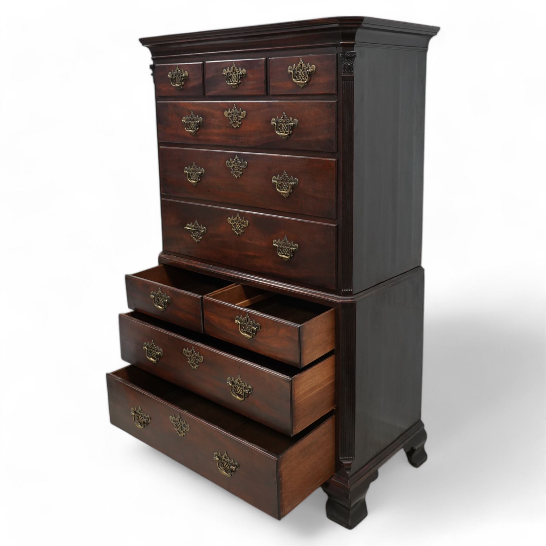 George III mahogany chest-on-chest, canted rectangular form, stepped cavetto moulded cornice, the upper section fitted with three short over three long drawers, the lower section fitted with two short over two long drawers, moulded drawer fronts with shaped and pierced handles plates and swan neck handles, enclosed by fluted corners with acanthus leaf capitals, on ogee bracket feet