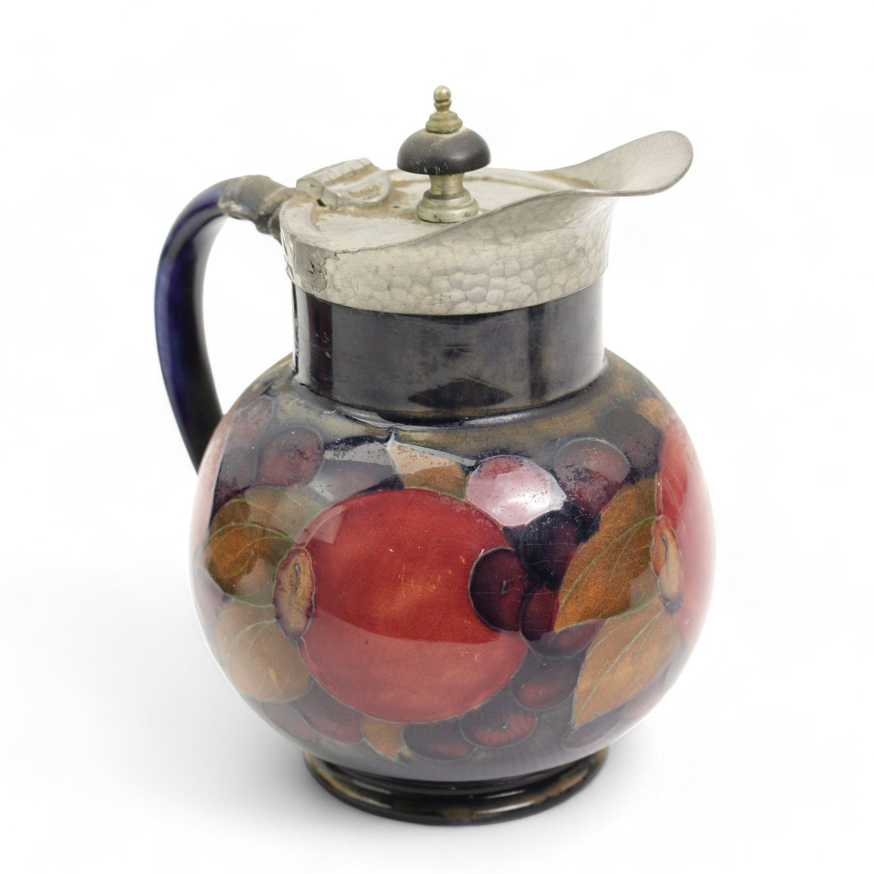 William Moorcroft Pomegranate pattern three piece tea service, comprising teapot with hammered pewter mounts and lid, sugar basin and hot water pot, all with pewter hammered finish mounts, possibly designed for Liberty & Co. 