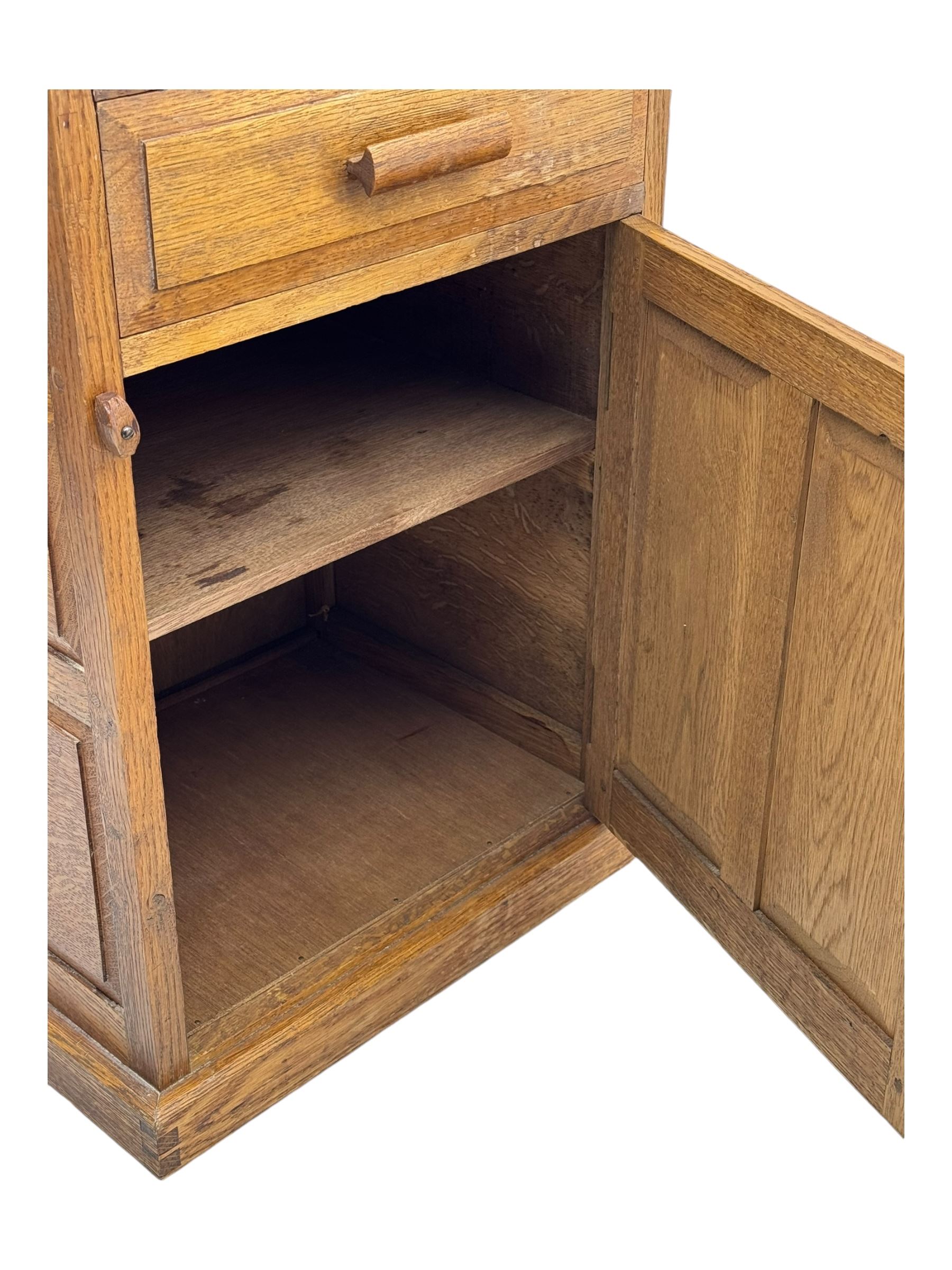 Arts & Crafts period oak bedside cupboard, raised back over moulded top, fitted with single drawer over panelled cupboard, panelled sides, on chamfered plinth base 