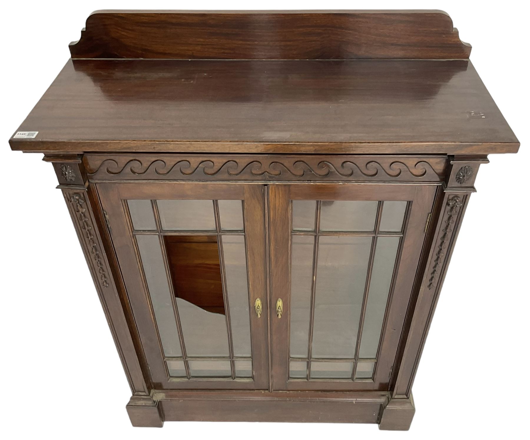 19th century mahogany display cabinet, rectangular top over frieze decorated with Vitruvian scroll mount, enclosed by two astragal glazed doors, the upright rails decorated with trailing bellflowers, on moulded plinth